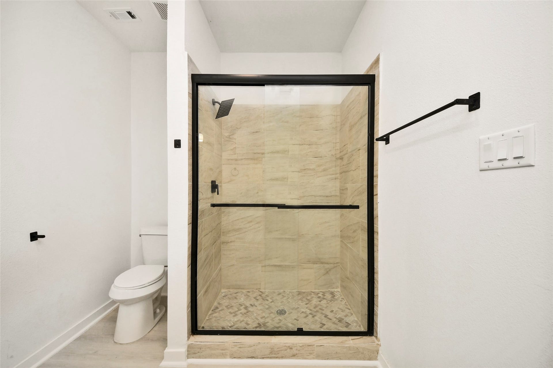 4615 Collingsworth Street, #AB, Houston, TX 77026 Modern bathroom featuring a sleek glass-enclosed shower with stylish tilework, complemented by a convenient adjacent toilet.