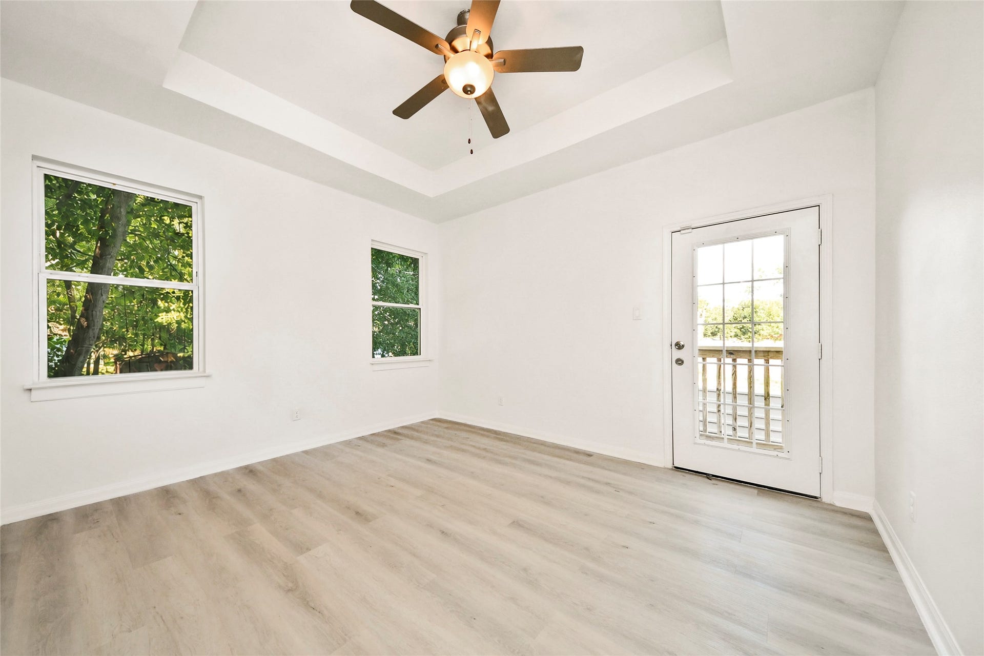 4615 Collingsworth Street, #AB, Houston, TX 77026 Bright and airy room featuring a stylish ceiling fan, light wood flooring, and ample natural light from large windows and a glass-paneled door leading to the outside.