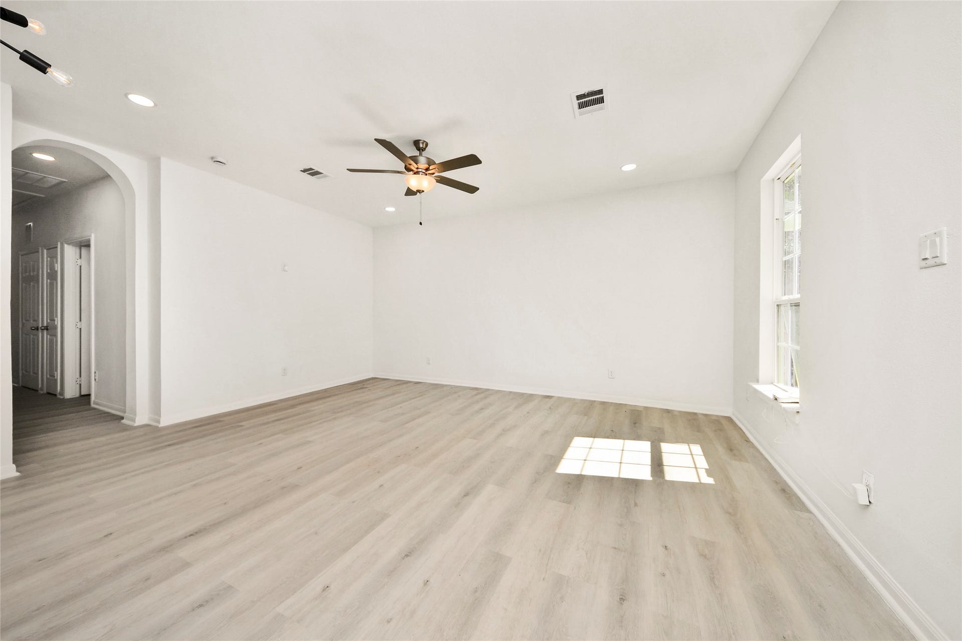 4615 Collingsworth Street, #AB, Houston, TX 77026 Spacious living area with sleek light wood flooring, a modern ceiling fan, and ample natural light streaming through large windows, perfect for relaxation and entertaining.