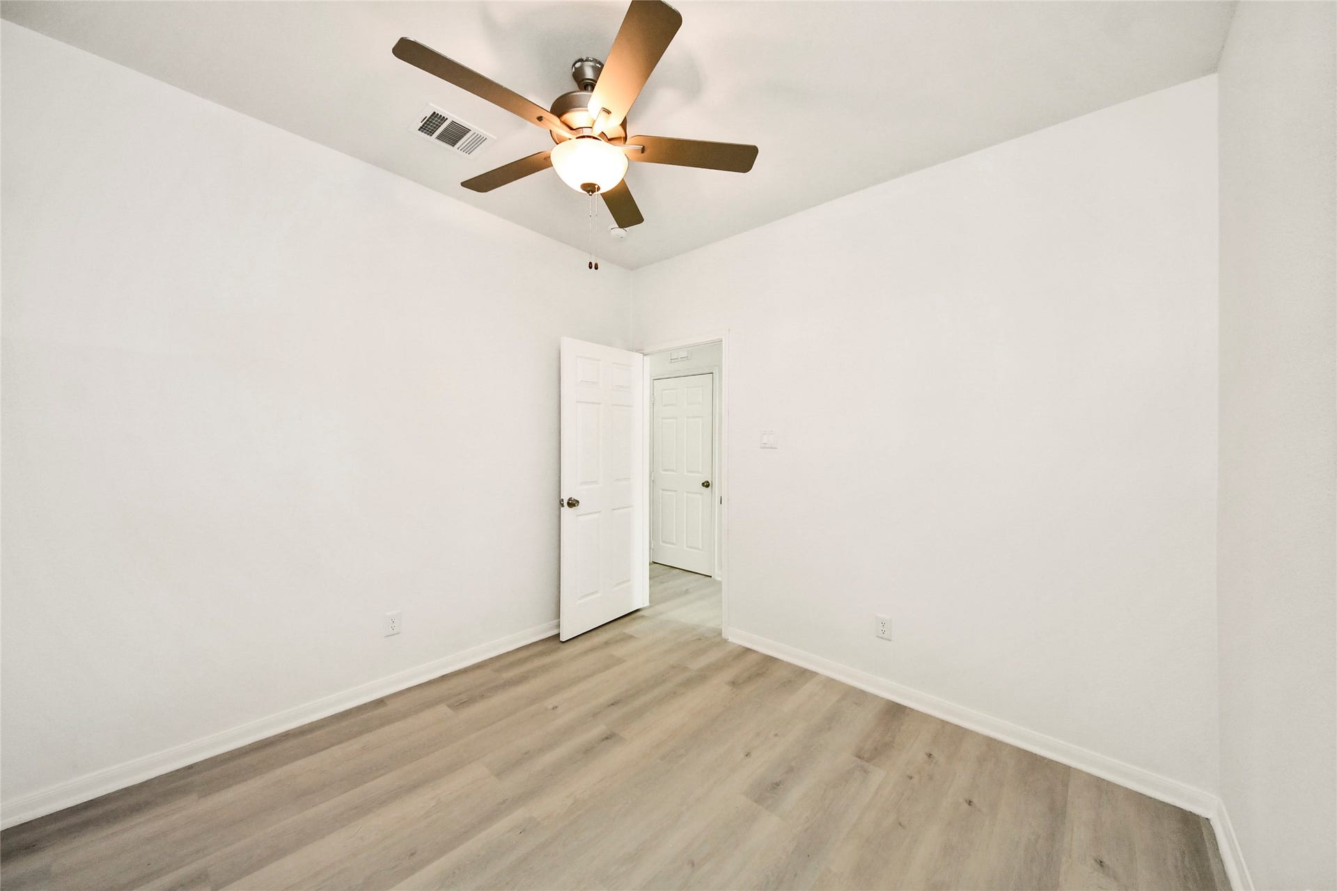 4615 Collingsworth Street, #AB, Houston, TX 77026 Bright and airy room featuring fresh white walls, sleek hardwood flooring, and a modern ceiling fan for comfort.
