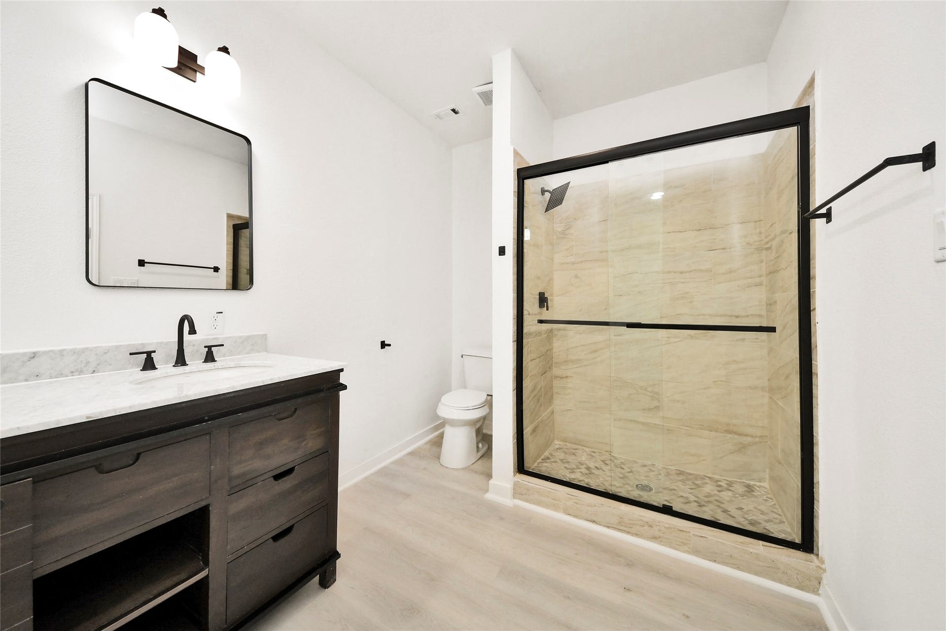 4615 Collingsworth Street, #AB, Houston, TX 77026 Modern bathroom featuring a sleek glass-enclosed shower, elegant dark wood vanity with marble countertop, and stylish fixtures.