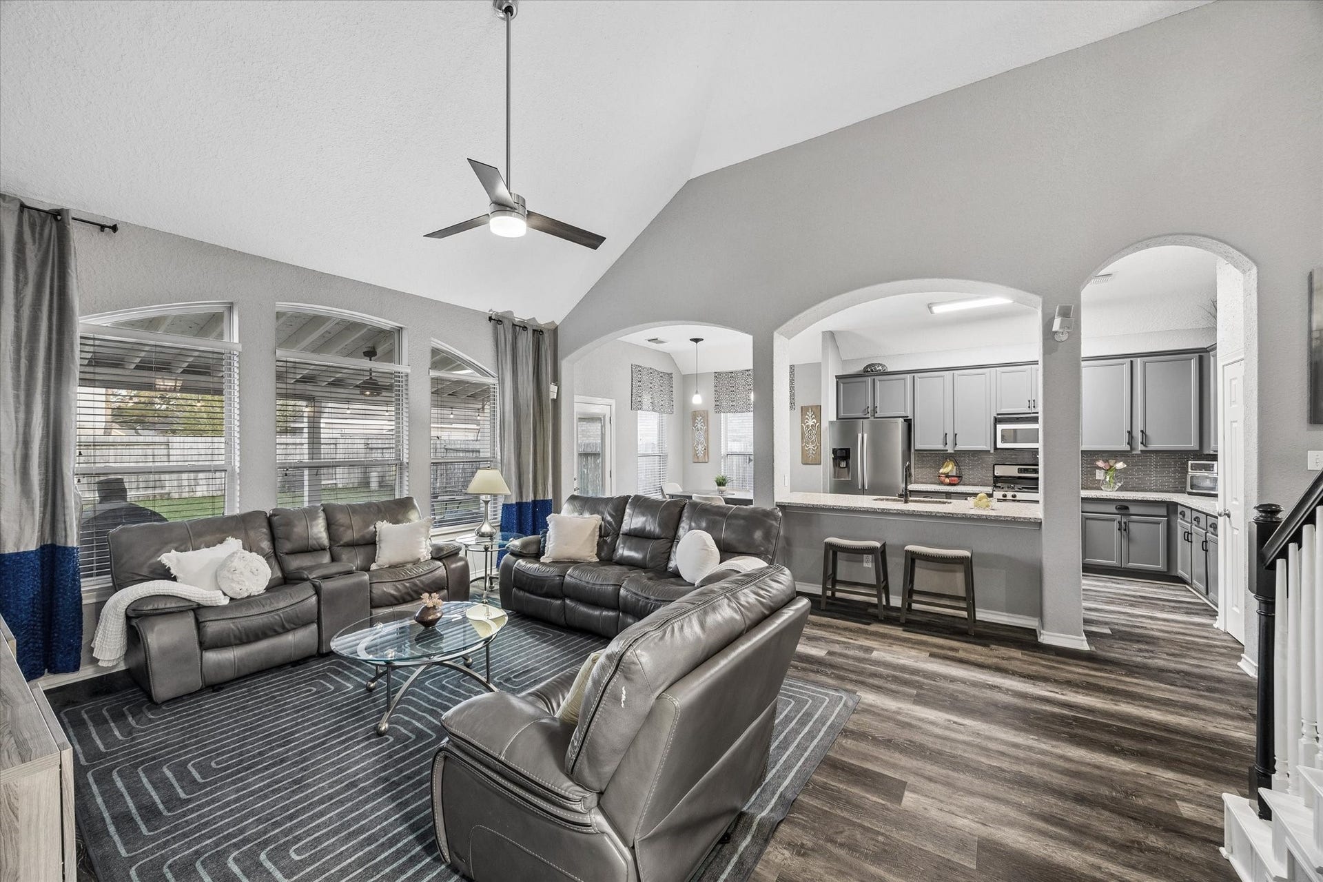 5115 Redleaf Forest Lane, Katy, TX 77494 This spacious family room features soaring vaulted ceilings and expansive windows that fill the space with natural light. The open-concept layout flows seamlessly into the kitchen, while charming arched openings and a convenient breakfast bar create an inviting atmosphere perfect for everyday living and entertaining.