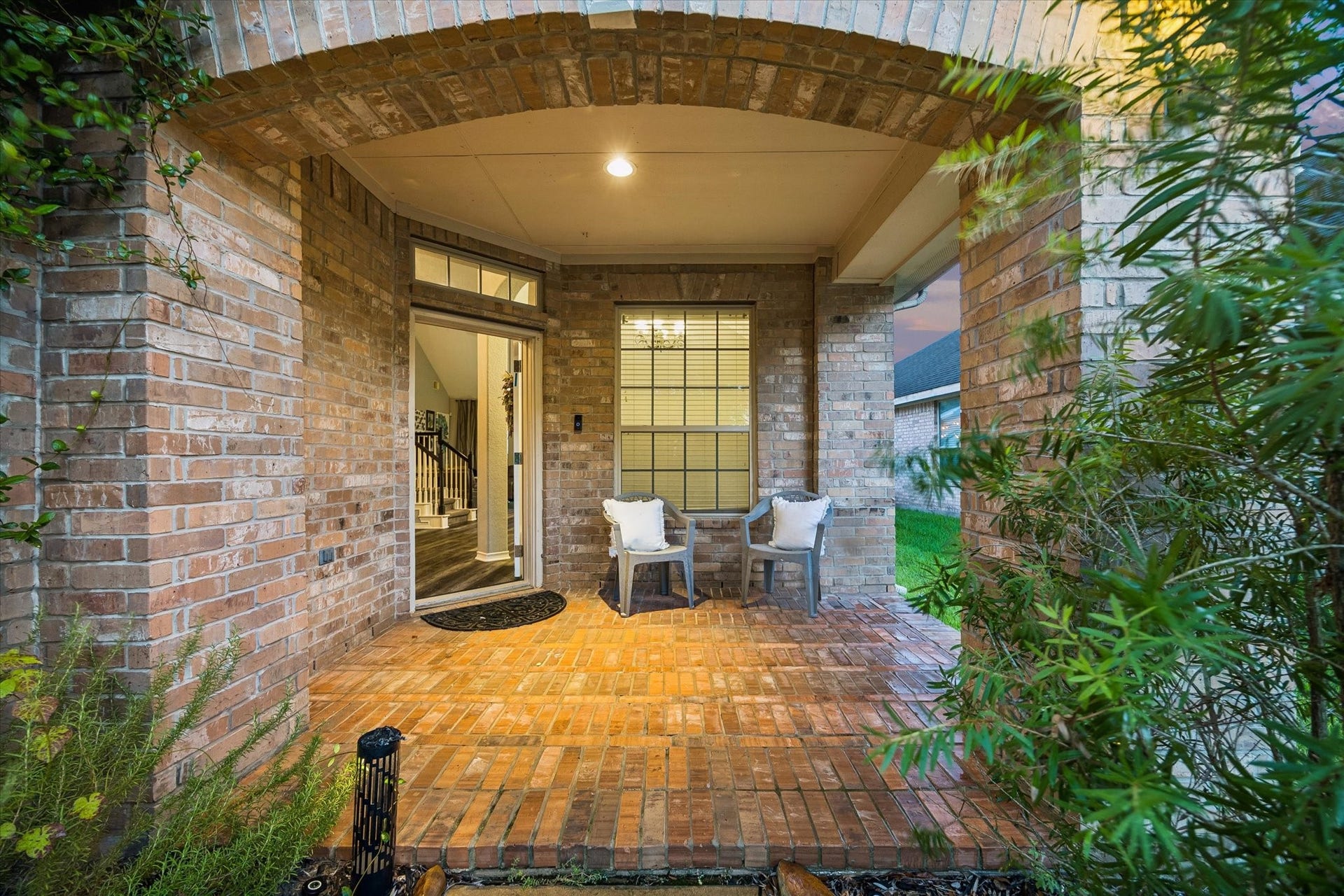 5115 Redleaf Forest Lane, Katy, TX 77494 A charming brick archway frames this beautiful covered front porch, creating a warm and inviting entrance to the home. Surrounded by lush greenery, this cozy outdoor retreat offers the perfect spot to relax and enjoy a peaceful morning or evening.
