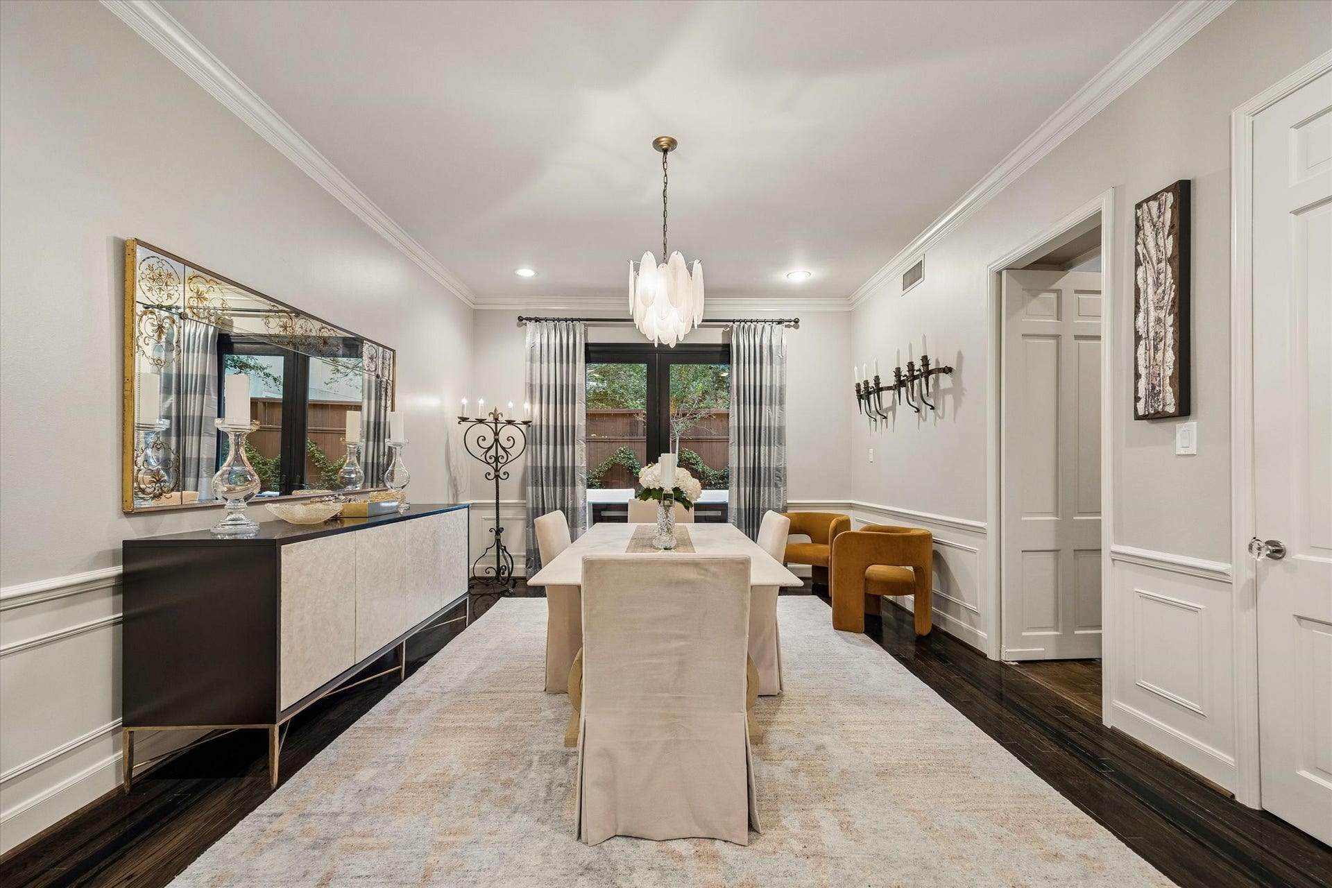 At the heart of the home is the Dining Room featuring hardwood floors, wainscoting with a chair rail topper and French doors that open to the Garden, which we will tour in a moment.  To the right of frame is a large Closet perfect for your serving pieces and table leaves.
