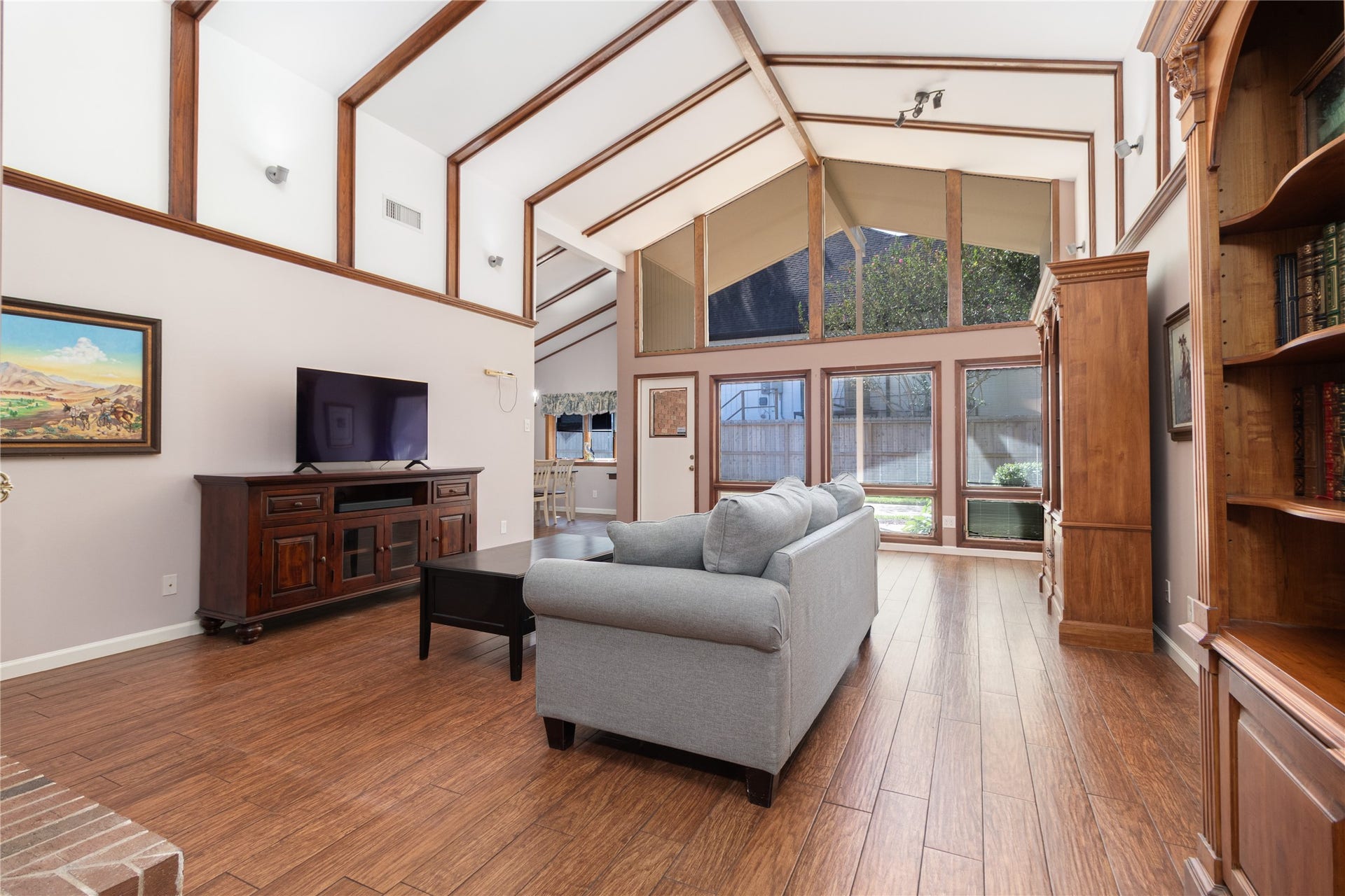 8919 Manhattan Drive, Houston, TX 77096 Soaring vaulted ceilings, exposed wood beams and a dramatic wall of windows define the spacious family room.