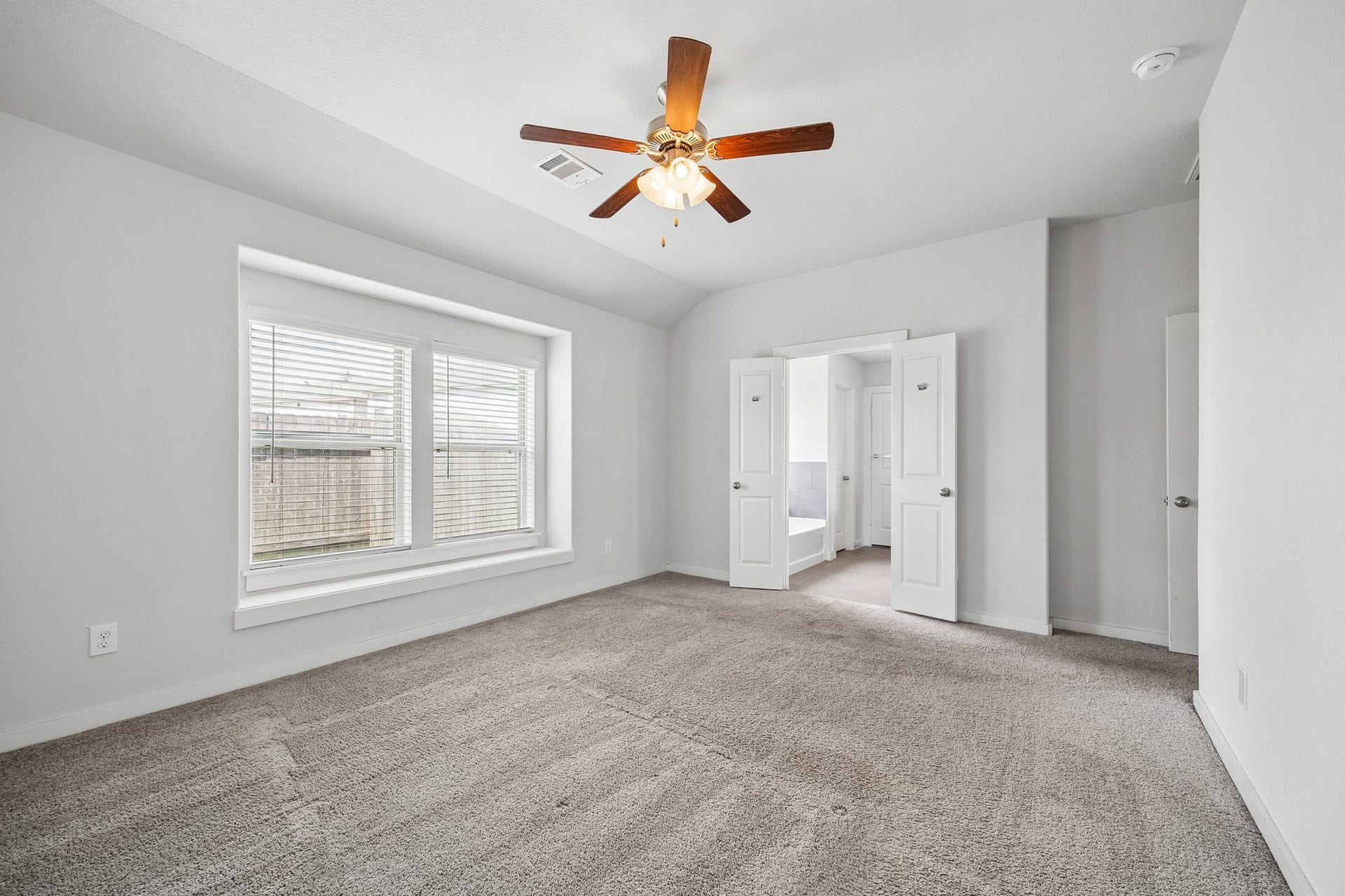 Recessed windows invite natural light into the primary bedroom and en-suite bathroom.
