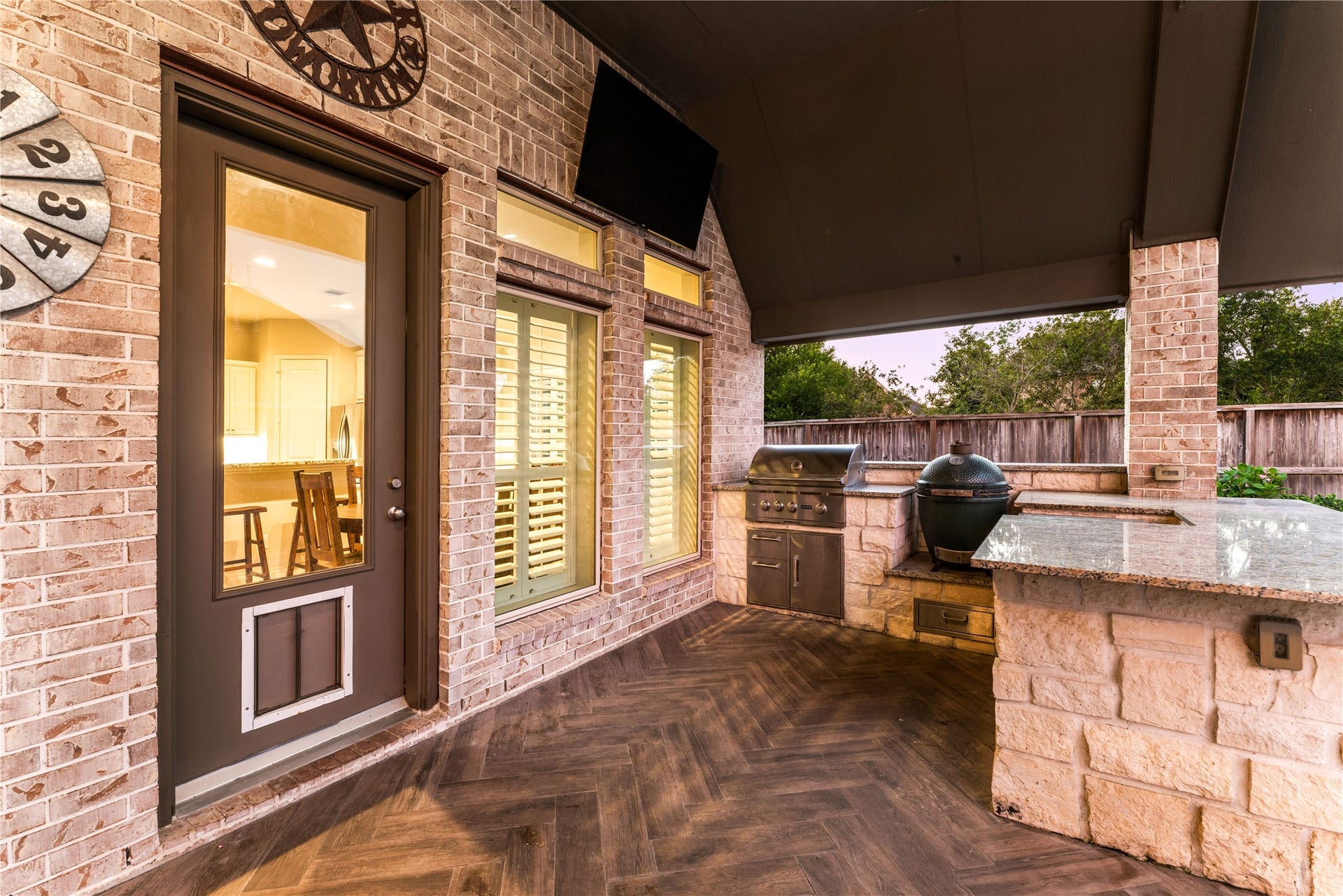 4103 August Light Court, Fulshear, TX 77441 Experience the pinnacle of year-round outdoor entertaining in this spectacular, fully covered luxury loggia and summer kitchen. A dramatic, dark-stained cathedral ceiling spans overhead, shielding the space from the elements while creating a striking, resort-style ambiance. The expansive outdoor cooking pavilion features built-in stainless steel appliances, a premium gas grill, flat top grill, and a massive wrap-around stone bar topped with durable solid-surface counters.