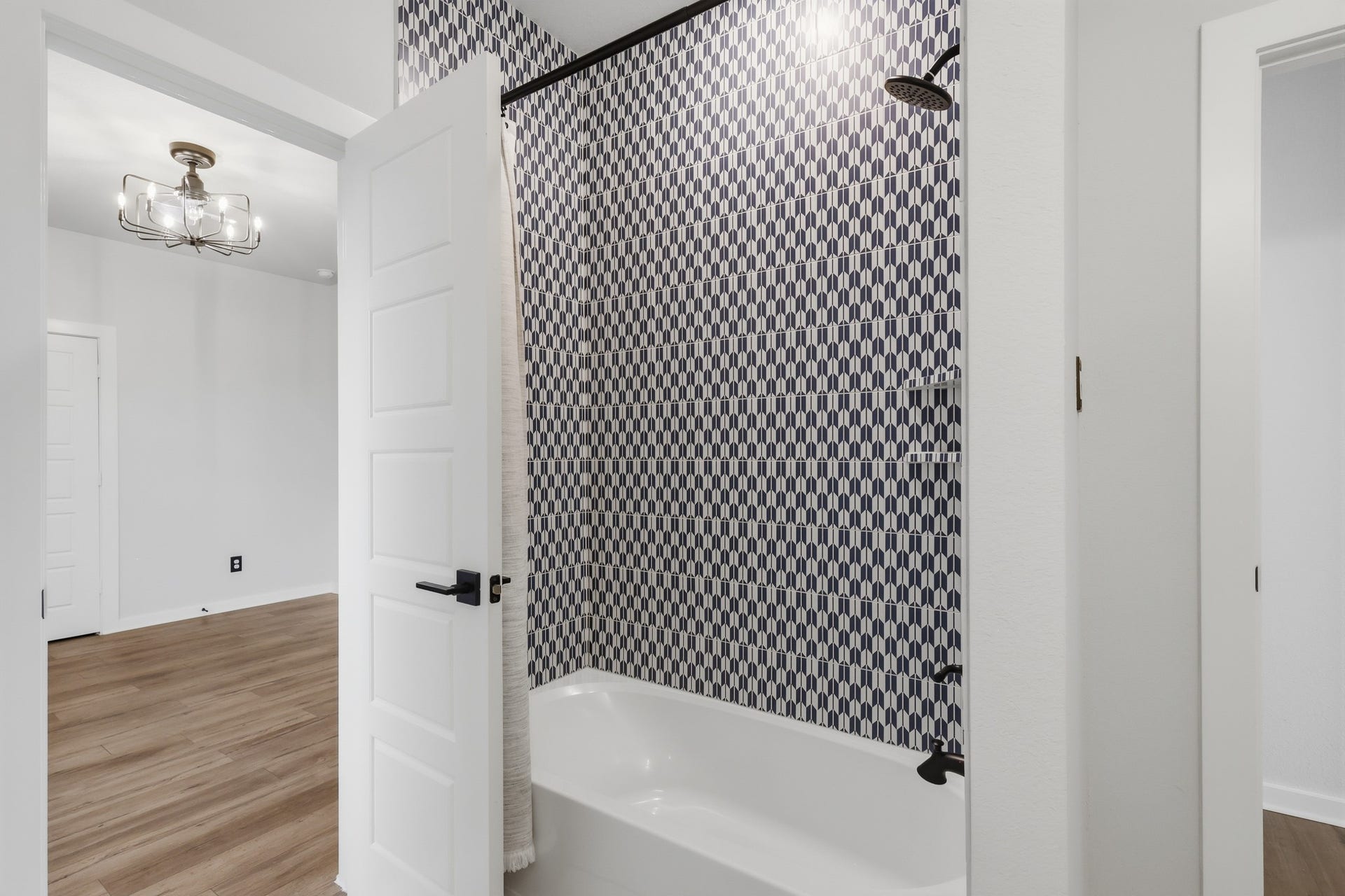 31539 Beacon Cove Trail, Fulshear, TX 77441 The shared bathroom features a tub and shower combination framed by bold geometric tile.