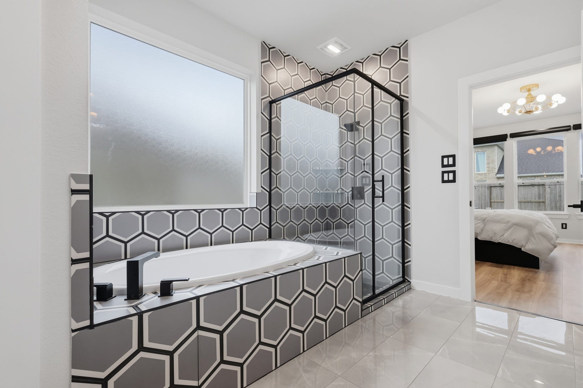 31539 Beacon Cove Trail, Fulshear, TX 77441 Geometric tile gives the tub and glass-enclosed shower a distinctive custom finish.