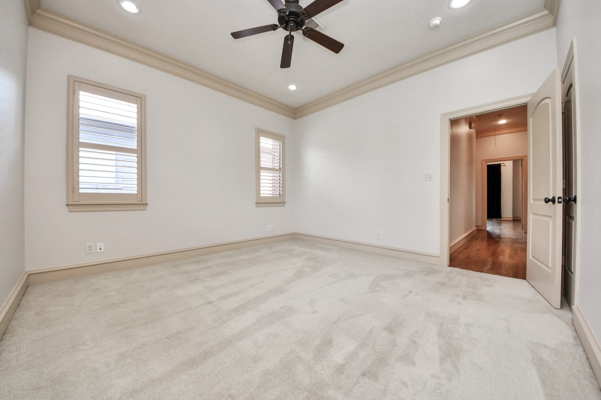 Spacious and bright room with plush carpeting, recessed lighting, and a ceiling fan, offering comfort and style.