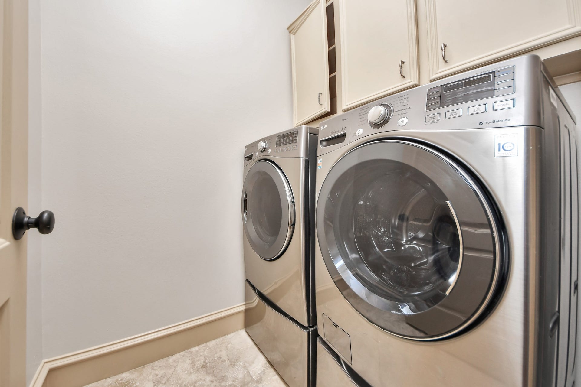 Modern laundry room featuring sleek stainless steel washer and dryer with ample cabinetry for storage.