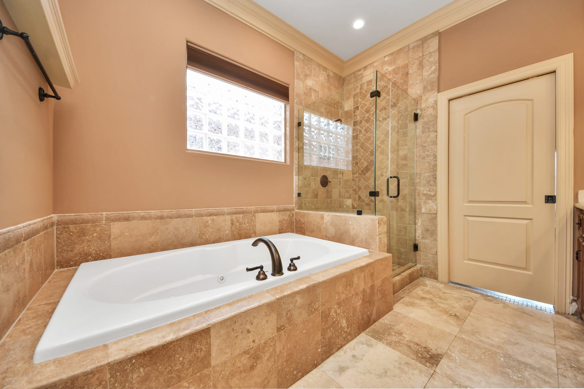 Luxurious bathroom featuring a spacious soaking tub and a sleek glass-enclosed shower, enhanced by elegant tilework and warm lighting.