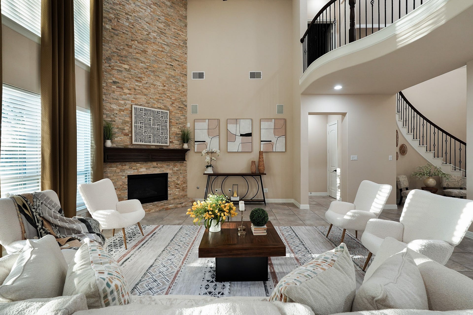 3102 Barrons Way, Sugar Land, TX 77479 This living room features a high ceiling, modern decor, and a stone accent wall with a fireplace. Large windows allow natural light to brighten the space. A curved staircase adds elegance, and the open layout is perfect for entertaining.