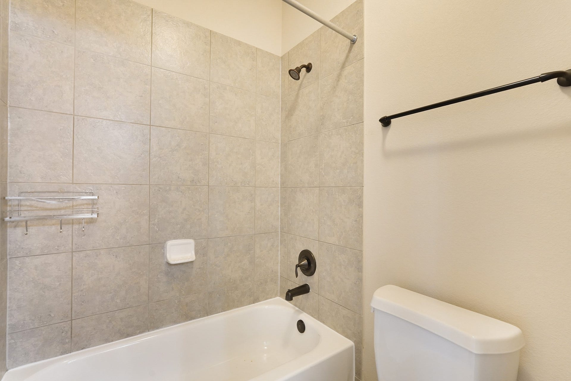 3102 Barrons Way, Sugar Land, TX 77479 SECOND Flr-Bath#4: This bathroom features a tiled shower and tub combo with a modern showerhead and fixtures. It includes a wall-mounted towel bar and a simple toilet, offering a clean and functional space.