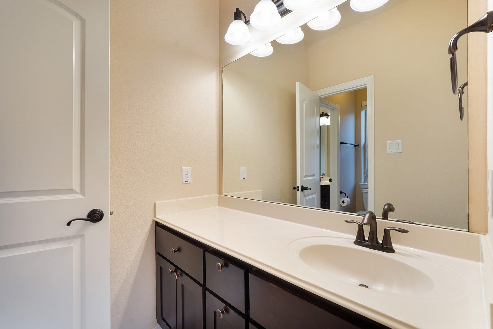 3102 Barrons Way, Sugar Land, TX 77479 SECOND Flr-Bath#4: This bathroom features a modern, clean design with a large mirror, ample countertop space, and dark wood cabinetry. The light fixtures add brightness, and there's a stylish sink with a sleek faucet.