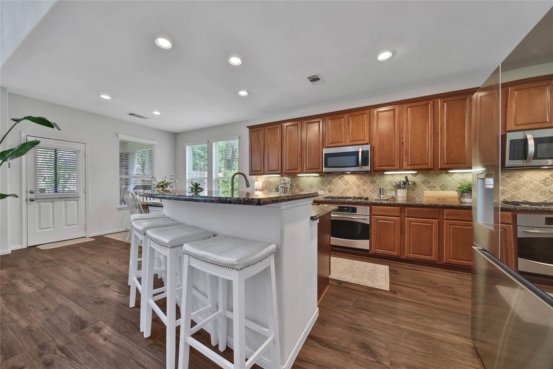 17311 Lassen Forest Lane, Humble, TX 77346 Recessed lighting, breakfast bar, wood cabinetry, gas cooking, island, under-cabinet lighting and tile backsplash - this kitchen delivers in its design aesthetic and functionality. Continuous wood tile floors create seamless flow between the rooms.