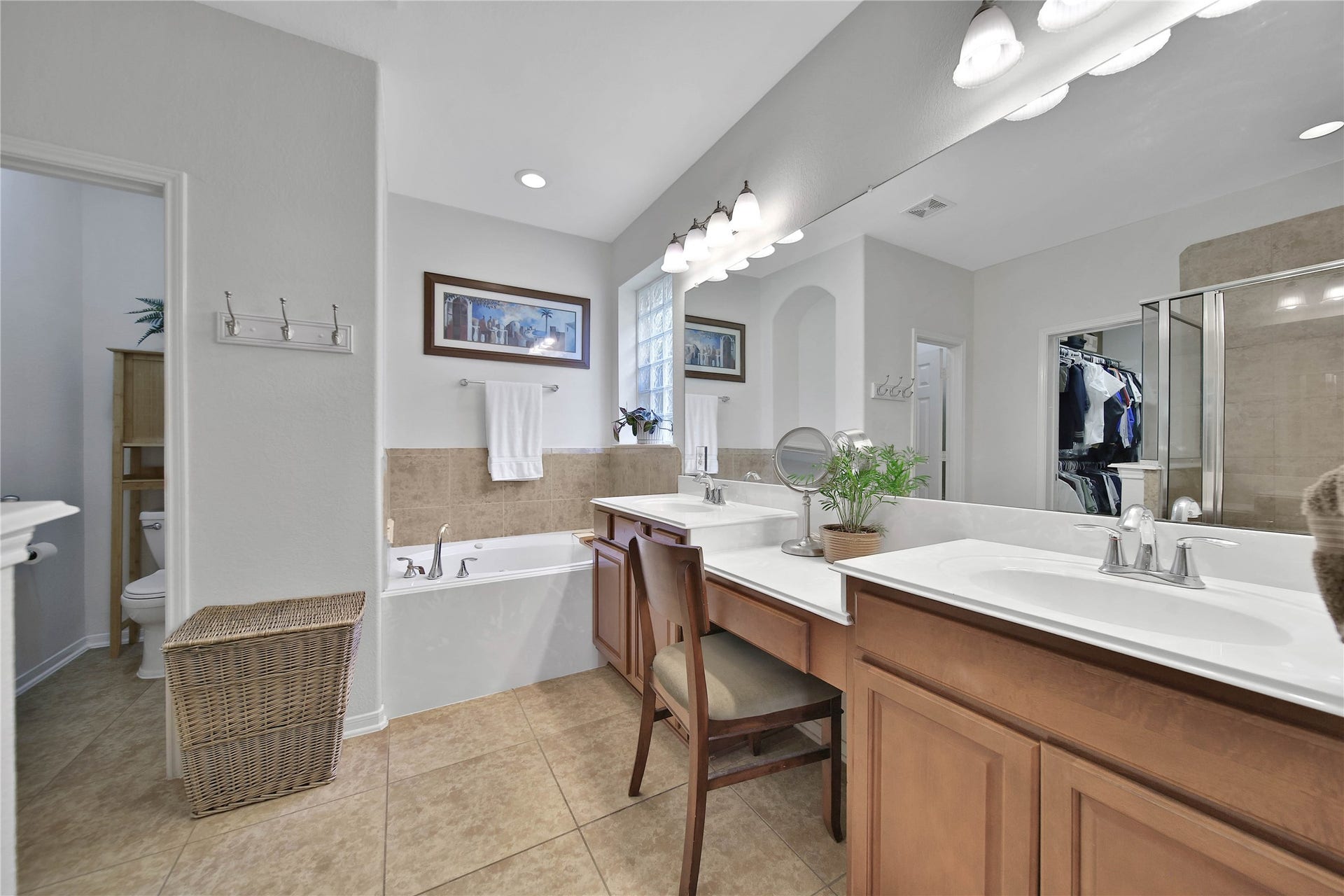 17311 Lassen Forest Lane, Humble, TX 77346 A glass block window overlooks the bathtub to bring in some soft natural light. Double sinks and a separate vanity area along with the wood cabinetry elevate this bath from the ordinary.
