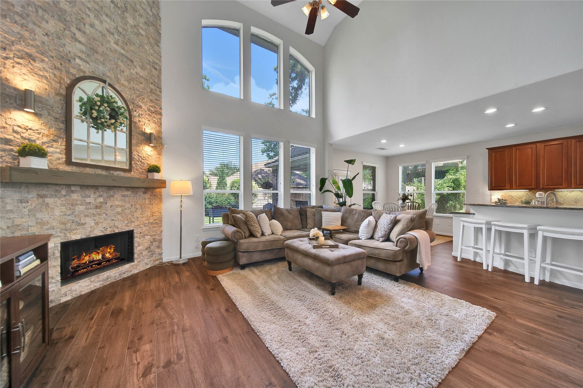 17311 Lassen Forest Lane, Humble, TX 77346 Stacked stone, wood mantle and gaslog fireplace make this spacious living room feel cozy and warm. The wood tile floors harmonize with the green scenery peeking in from the outdoors. The open concept kitchen / living room keep these spaces connected and add to the spacious feel.