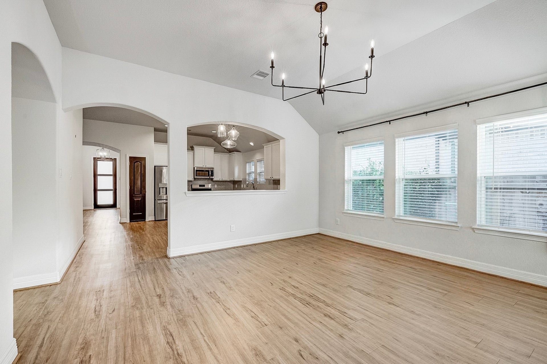 40638 Goldeneye Place, Magnolia, TX 77354 Bright and airy dining area with elegant hardwood flooring, a modern chandelier, and large windows offering ample natural light, seamlessly connected to the open kitchen and living space.