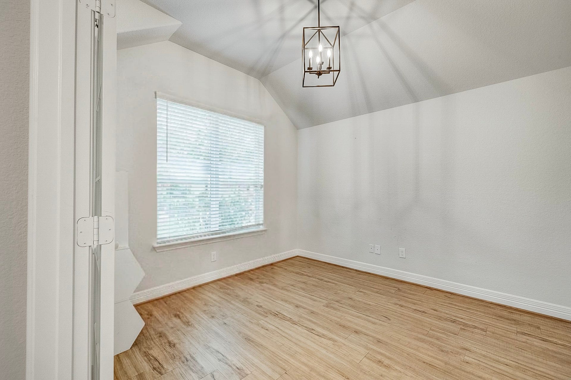 40638 Goldeneye Place, Magnolia, TX 77354 Bright and inviting room featuring a modern light fixture, vaulted ceiling, and elegant wood flooring, perfect for an office or cozy retreat.
