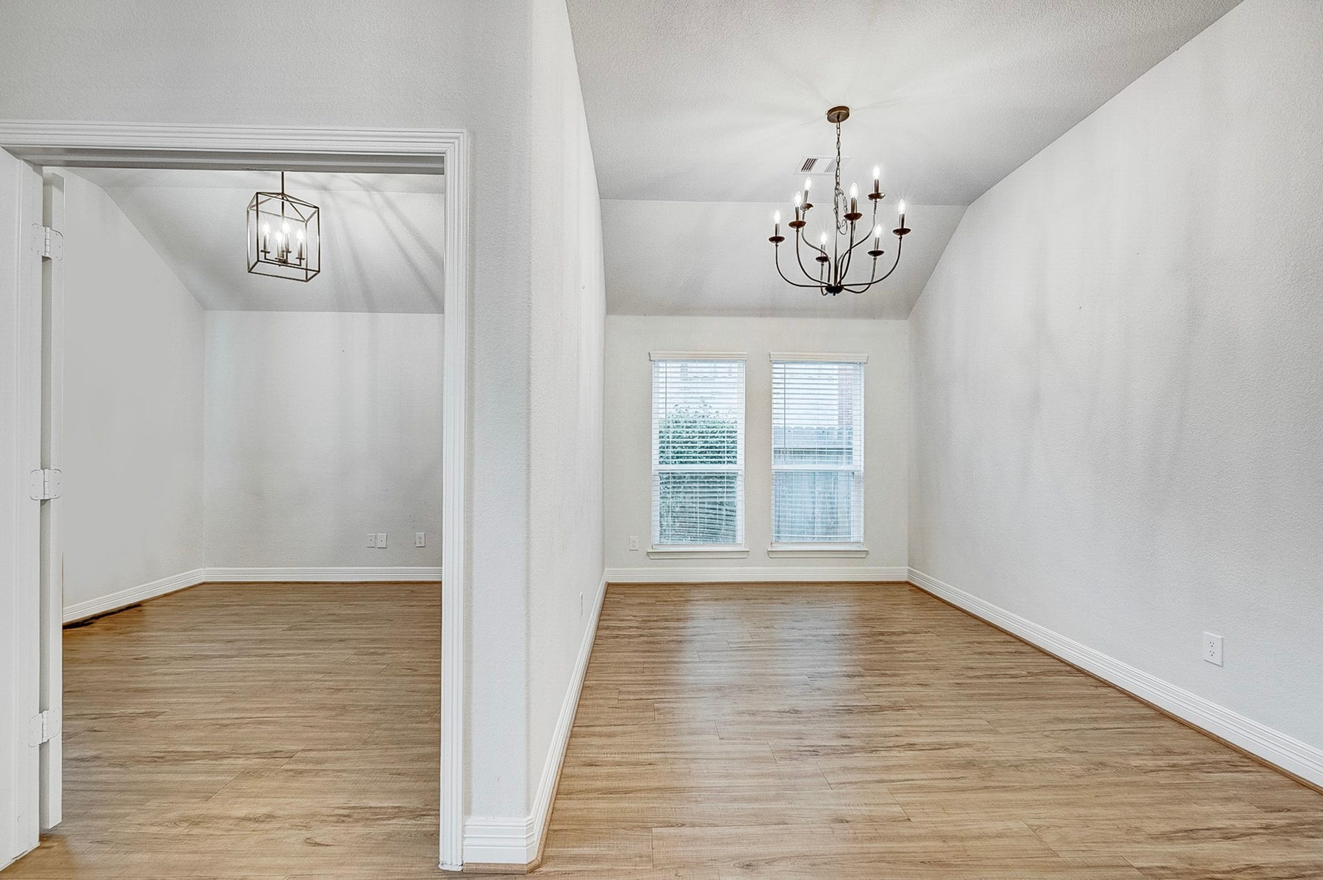 40638 Goldeneye Place, Magnolia, TX 77354 Bright and inviting dining area with wood flooring, elegant chandelier, and large windows for natural light. Adjacent space offers flexible use with modern lighting.