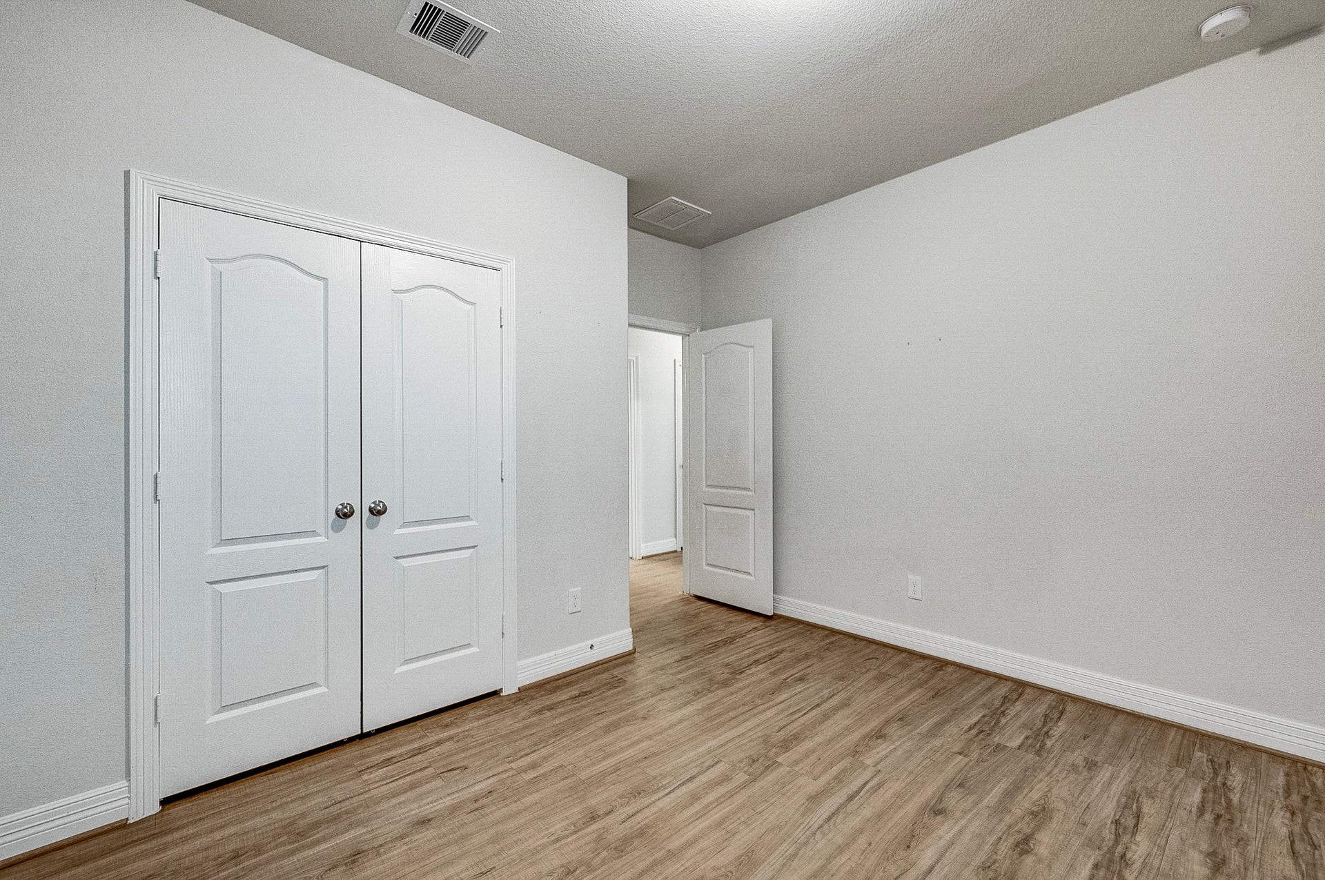 40638 Goldeneye Place, Magnolia, TX 77354 Spacious room with elegant wood flooring and a double-door closet, offering ample storage and a fresh, modern feel.