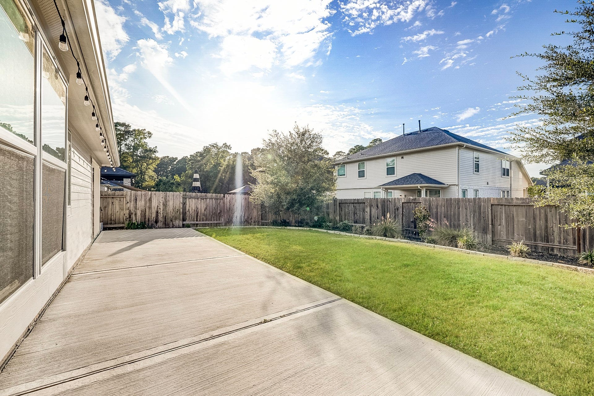 40638 Goldeneye Place, Magnolia, TX 77354 Expansive backyard with a spacious concrete patio, perfect for outdoor entertaining, complemented by a well-maintained lawn and surrounded by a privacy fence.