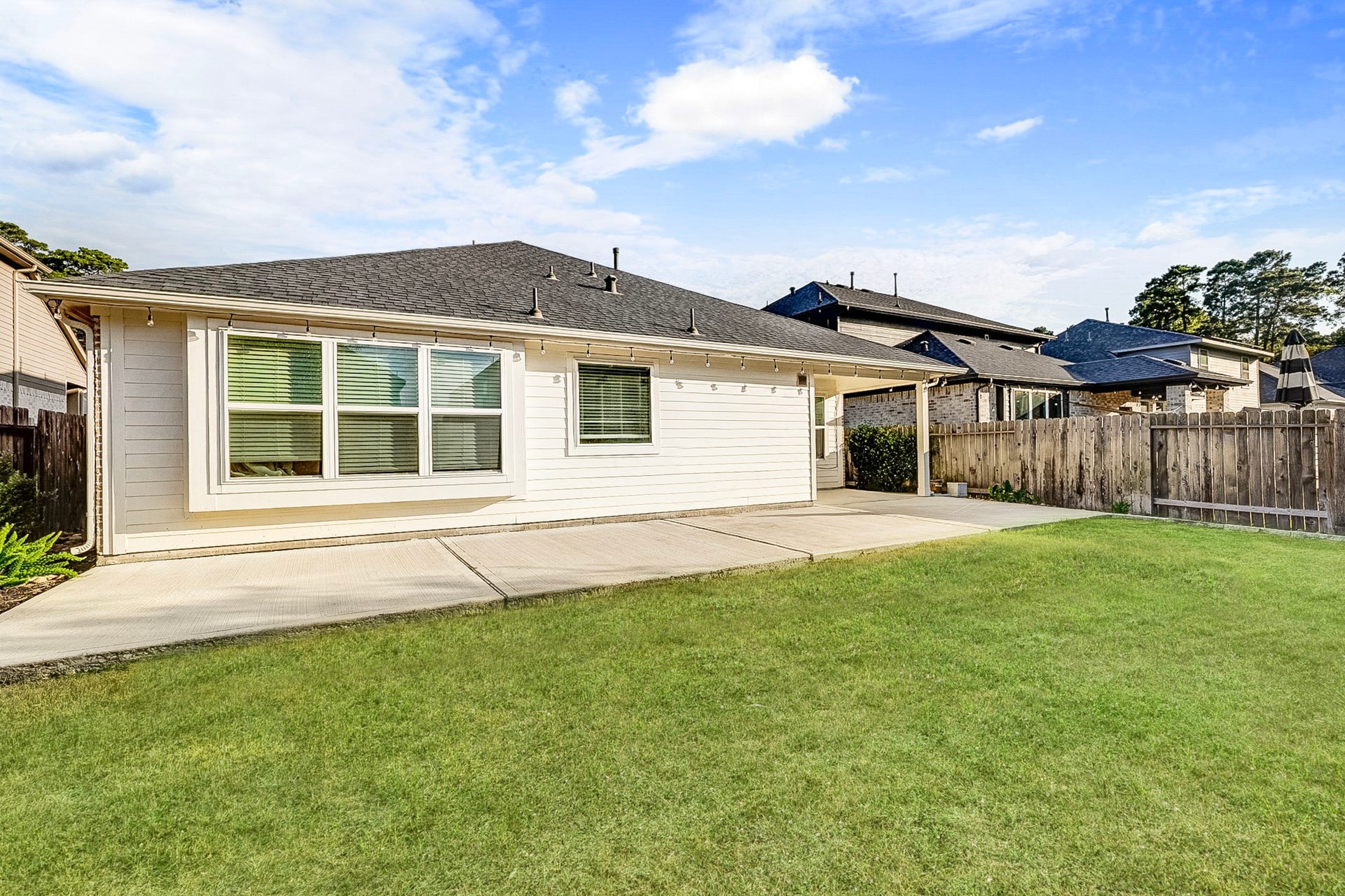40638 Goldeneye Place, Magnolia, TX 77354 Charming backyard with a spacious patio, perfect for outdoor entertaining, bordered by a wooden fence for privacy and surrounded by lush greenery.