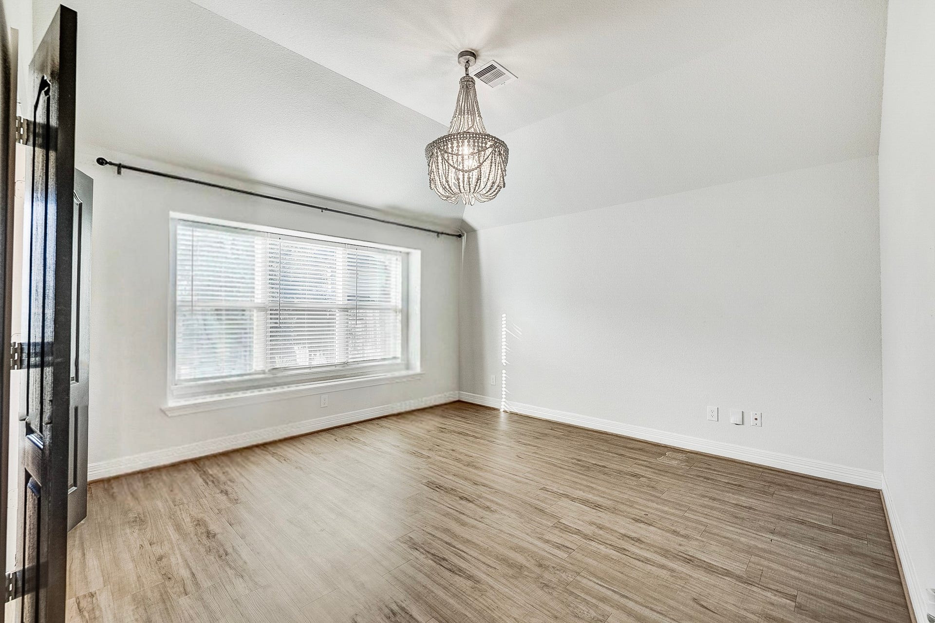 40638 Goldeneye Place, Magnolia, TX 77354 Bright and spacious room featuring elegant wood flooring, a large window with abundant natural light, and a stylish chandelier accentuating the high ceiling.