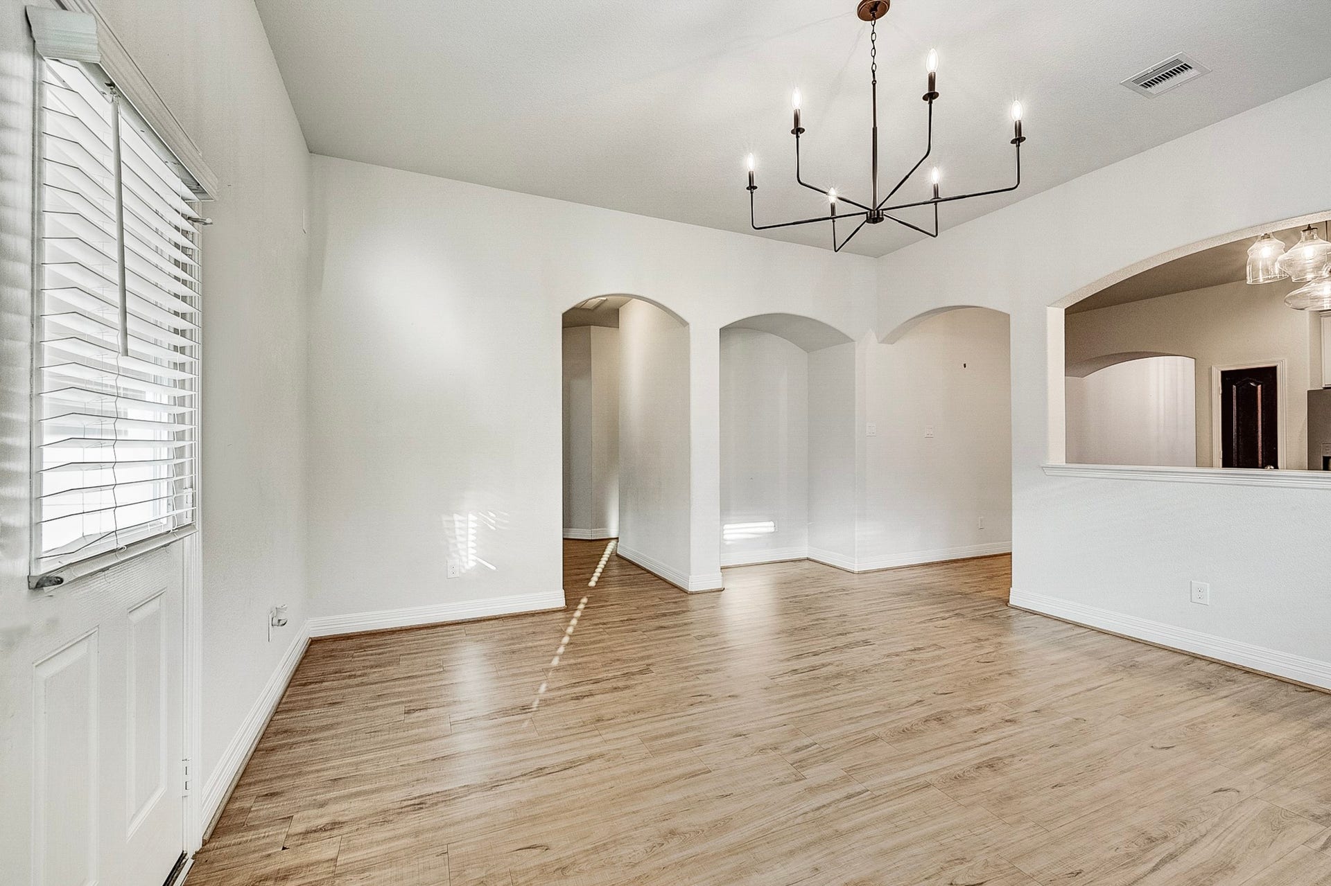 40638 Goldeneye Place, Magnolia, TX 77354 Elegant dining area with modern chandelier, hardwood floors, and arched doorways offering a spacious and inviting atmosphere.