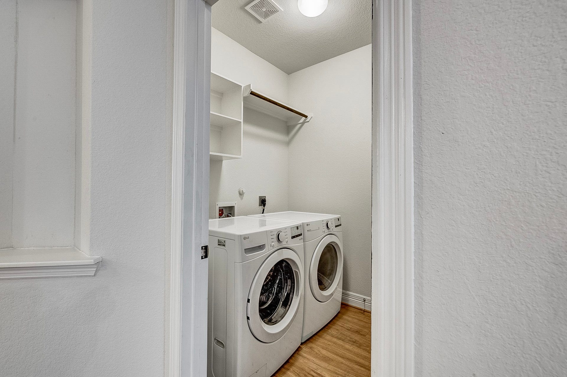 40638 Goldeneye Place, Magnolia, TX 77354 Efficient laundry room with modern washer and dryer, open shelving, and a hanging rod for convenience.