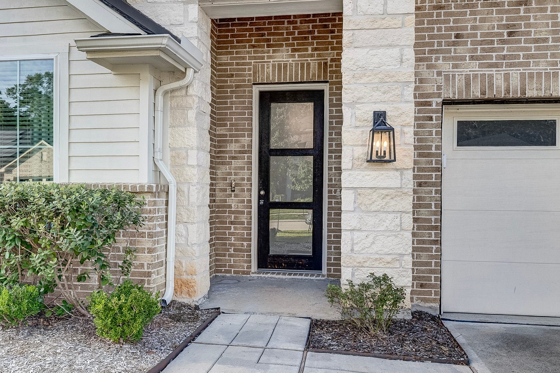 40638 Goldeneye Place, Magnolia, TX 77354 Charming front entrance featuring a modern glass door, elegant brick and stone accents, and a stylish outdoor light fixture.