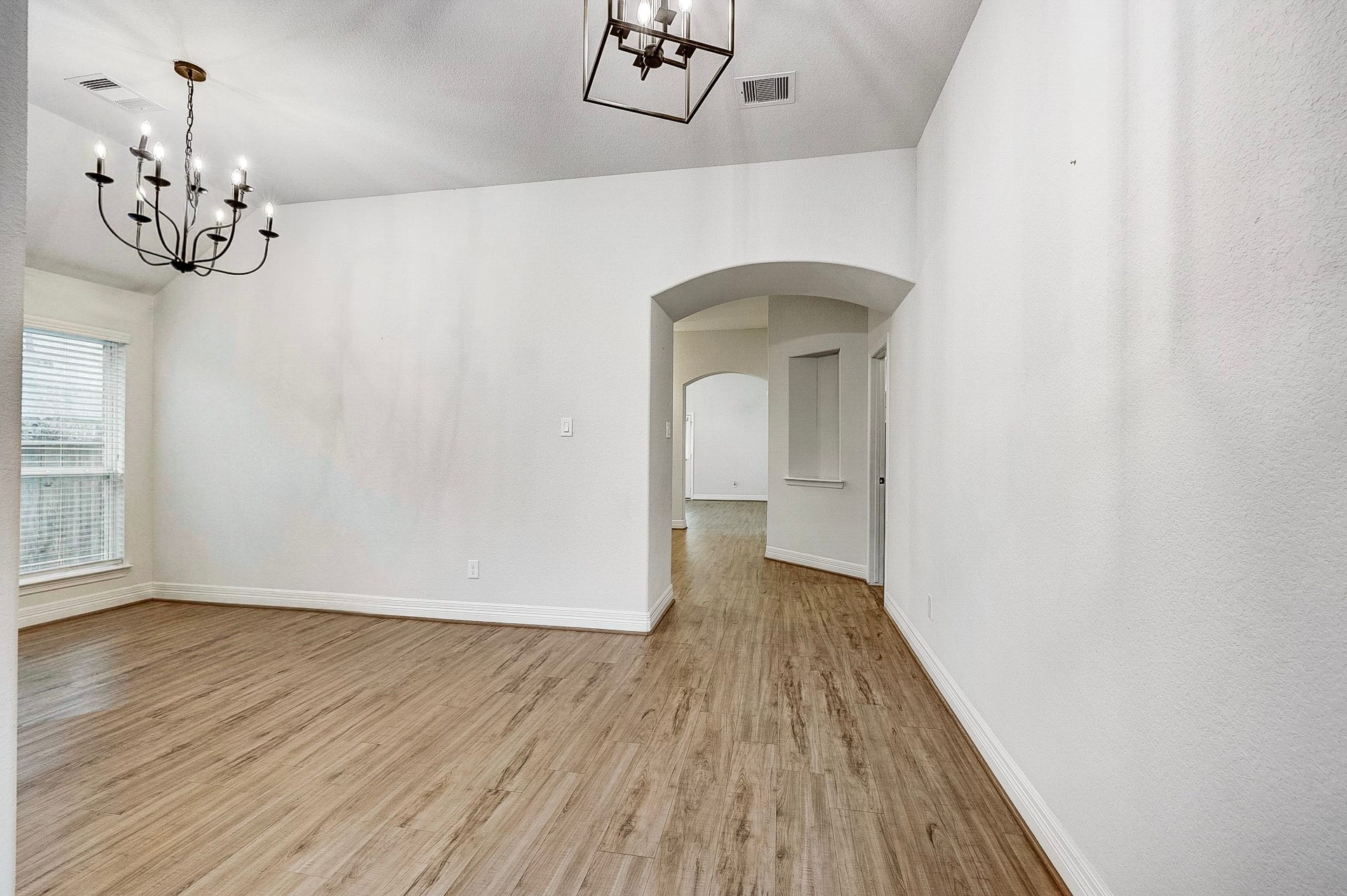 40638 Goldeneye Place, Magnolia, TX 77354 Spacious room with elegant chandeliers, wood flooring, and arched entryways, offering a bright and inviting atmosphere.