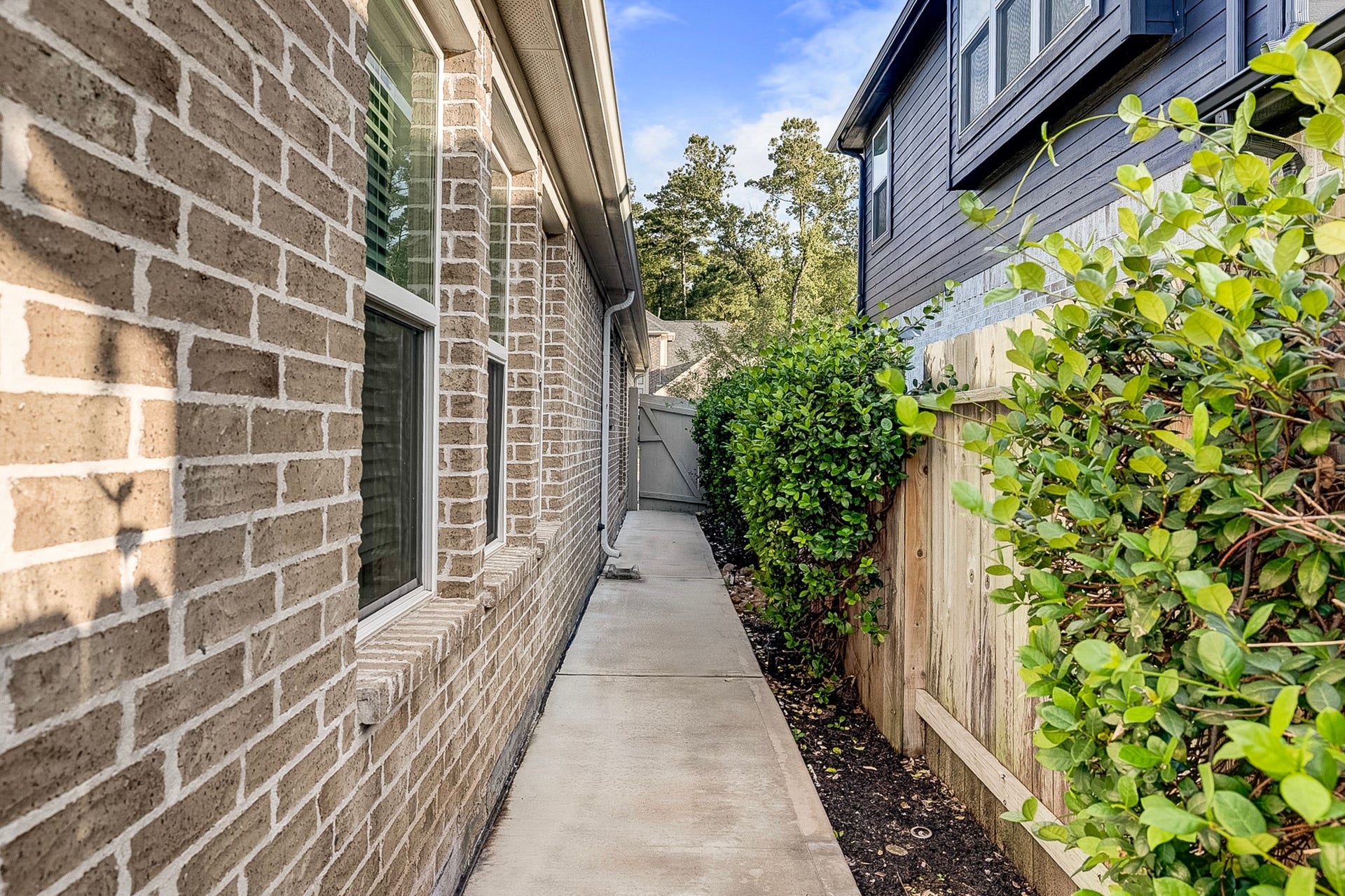 40638 Goldeneye Place, Magnolia, TX 77354 Charming side pathway with brick exterior and lush greenery, leading to a private backyard.