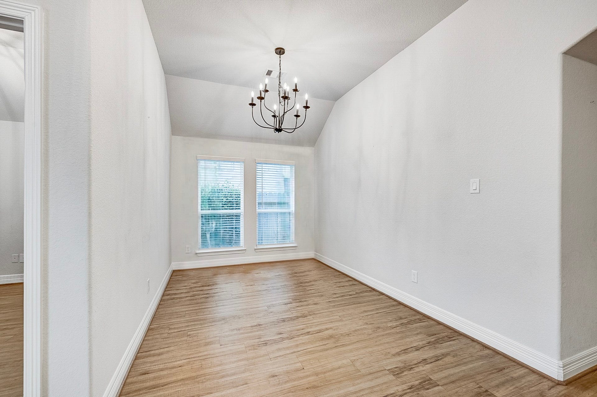 40638 Goldeneye Place, Magnolia, TX 77354 Elegant dining room featuring a stylish chandelier, vaulted ceiling, and abundant natural light through large windows, complemented by beautiful wood flooring.