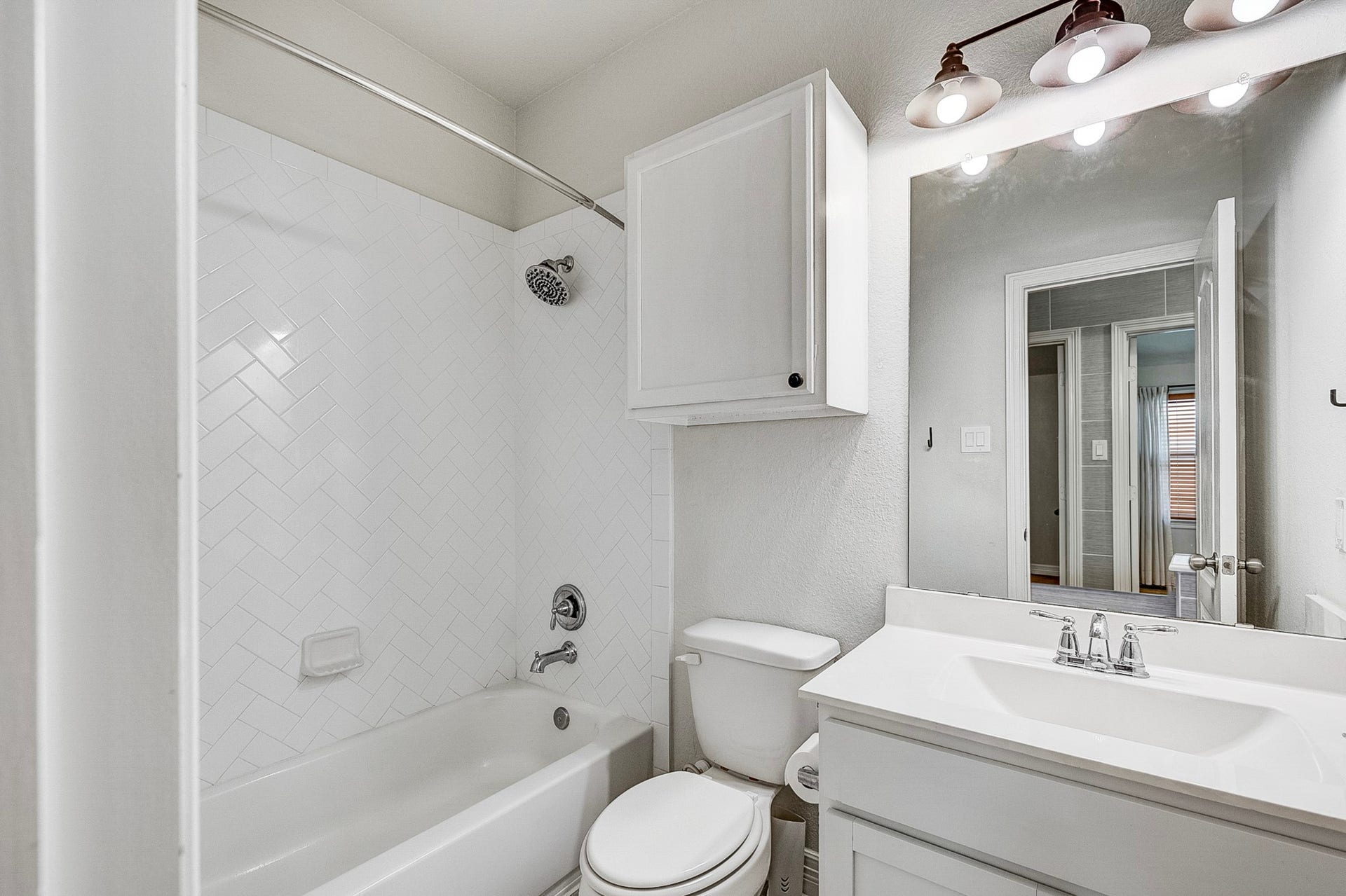 40638 Goldeneye Place, Magnolia, TX 77354 Bright and modern bathroom featuring a sleek vanity, spacious mirror, and a classic white-tiled shower-tub combo.