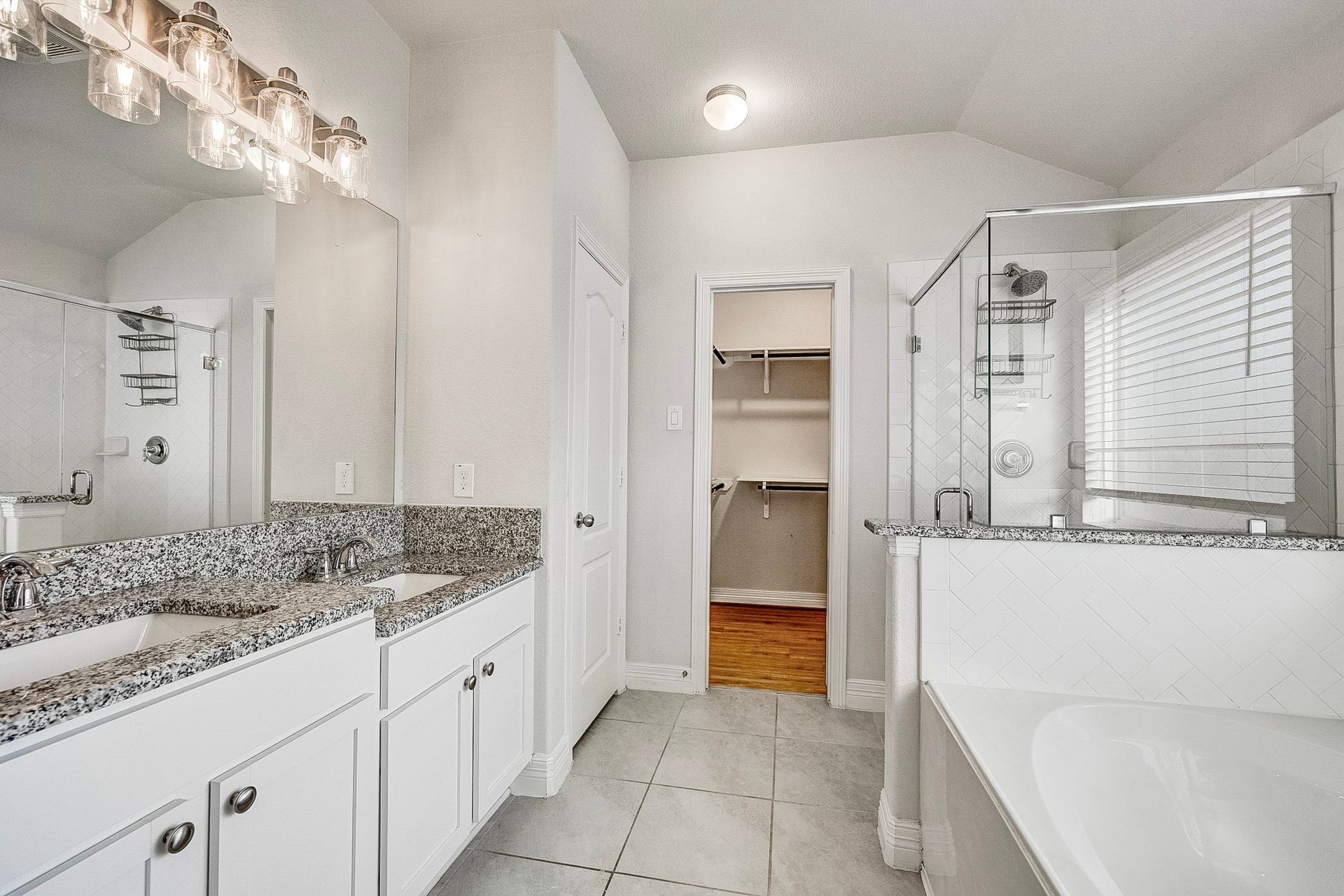 40638 Goldeneye Place, Magnolia, TX 77354 Elegant bathroom featuring a dual-sink vanity with granite countertops, a spacious glass-enclosed shower, and direct access to a walk-in closet.