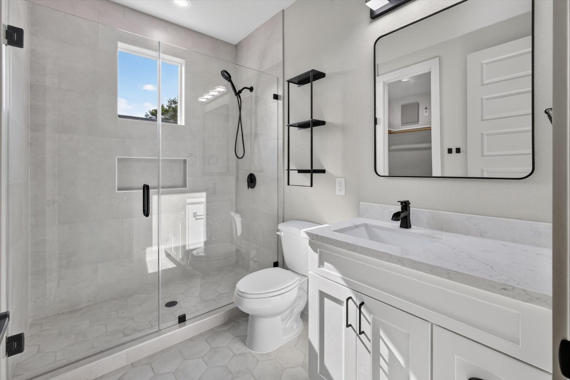 8027 BETTY BOOP Street, Houston, TX 77028 This modern bathroom features a sleek glass-enclosed shower with green tile, a stylish vanity with ample storage, and a neutral color palette. The space is enhanced by elegant fixtures and tasteful decor, creating a clean and inviting atmosphere.