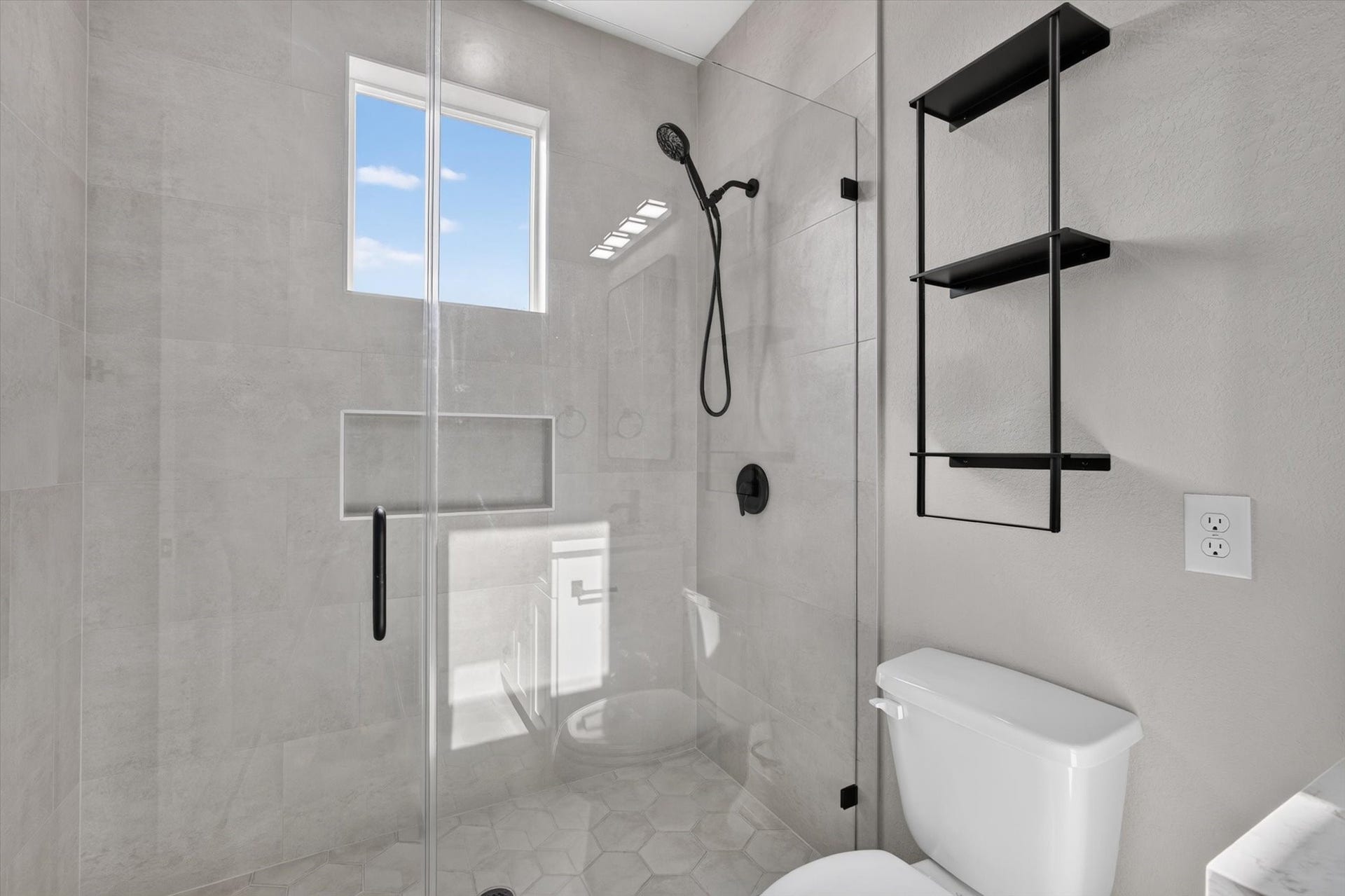 8027 BETTY BOOP Street, Houston, TX 77028 This modern bathroom features a sleek wooden vanity with a white countertop and a rectangular mirror. A neutral gray wall complements the clean design, and a touch of greenery adds a fresh accent.