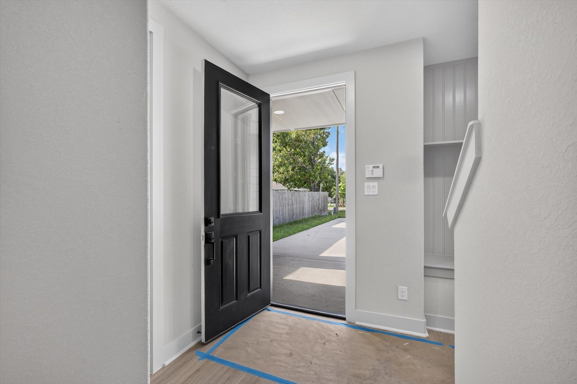 8027 BETTY BOOP Street, Houston, TX 77028 This entryway features a modern design with a large windowed door, stylish dark walls, and wood flooring. There is a cozy nook with seating and shelving, plus a small window for natural light. A staircase leads upward, adding to the home's welcoming ambiance.