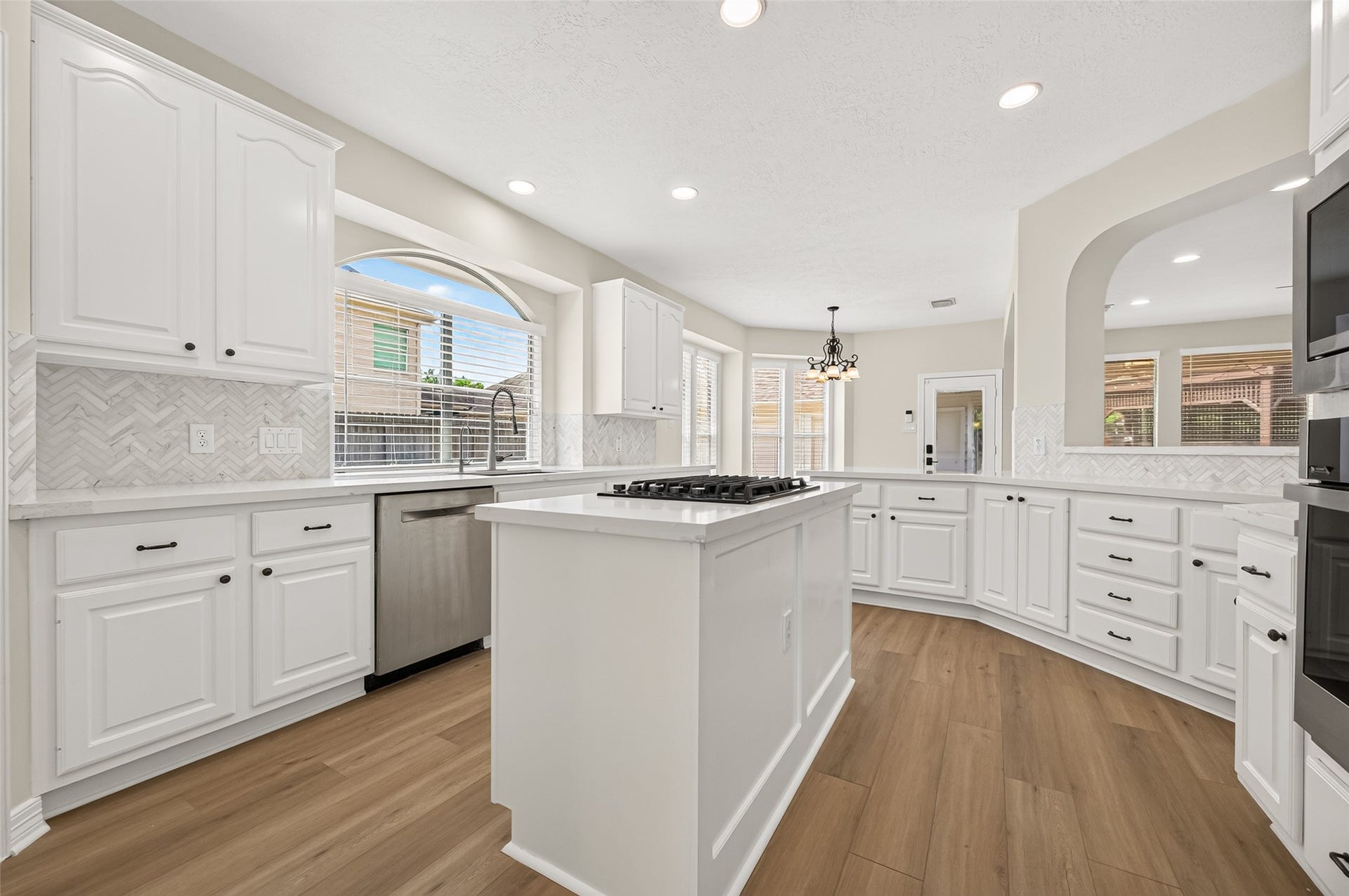 826 Ivory Ridge Lane, Houston, TX 77094 BRIGHT & BEAUTIFUL! The updated island kitchen feels fresh and inviting with quartz countertops (2026), stacked quartz tile backsplash (2026), freshly painted white cabinetry (2026), & updated hardware. Recessed lighting adds plenty of illumination, while the large arched window above the sink fills the kitchen with natural light. A wonderful combination of timeless style & thoughtful updates.