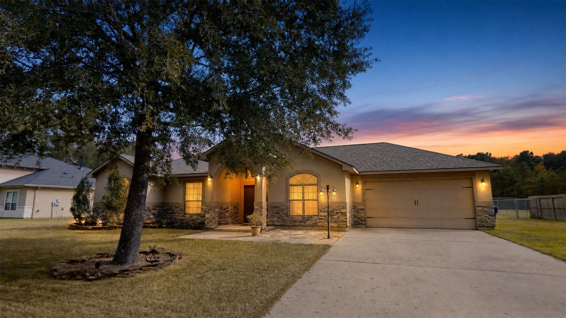 27628 Rio Blanco Drive, Splendora, TX 77372 Charming single-story home with stone accents, nestled under a mature tree, featuring a welcoming front porch and spacious driveway.