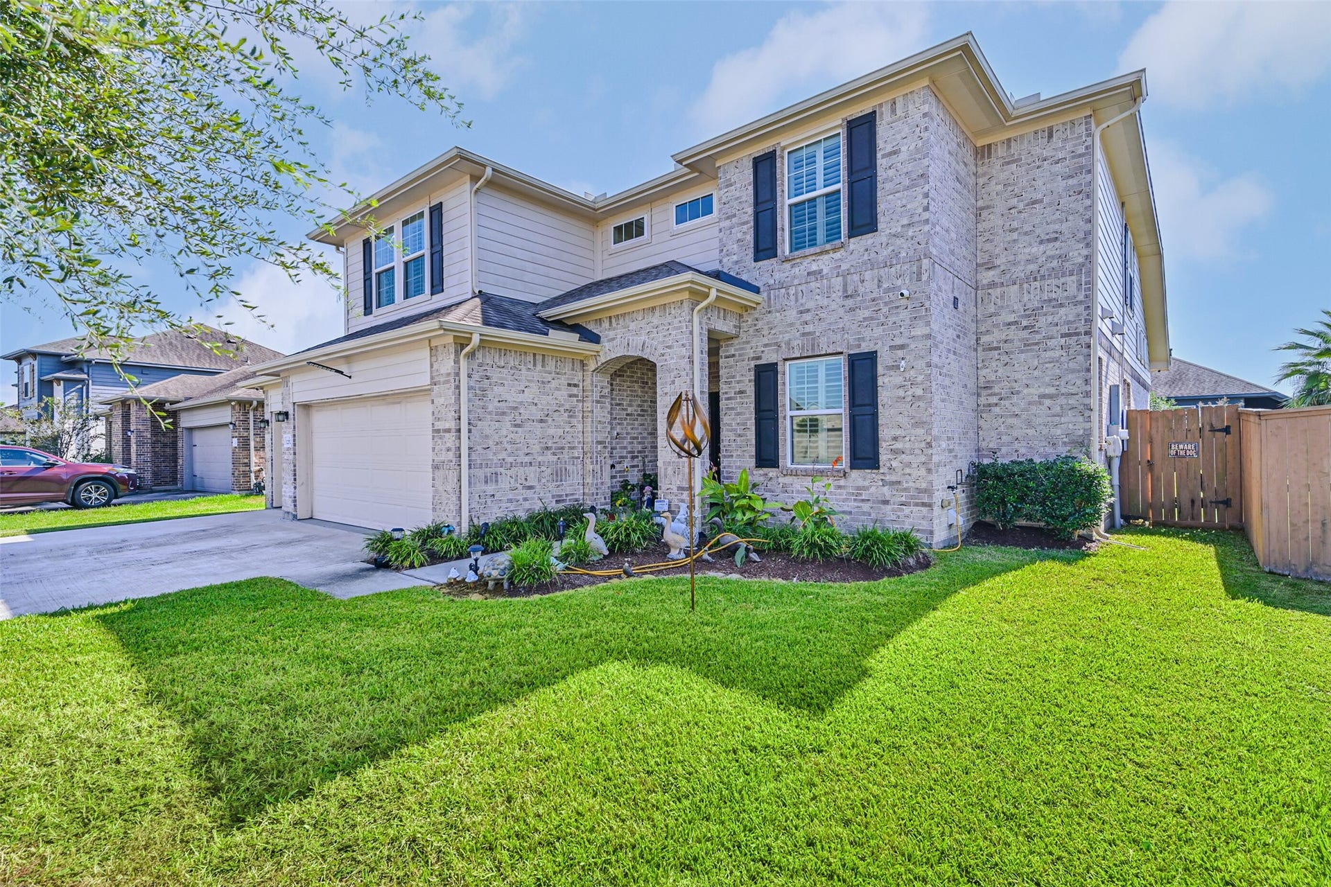 12527 Jetty Cove Drive, Texas City, TX 77568 Attractive brick exterior with landscaped flower beds, mature greenery, and a welcoming covered entryway.