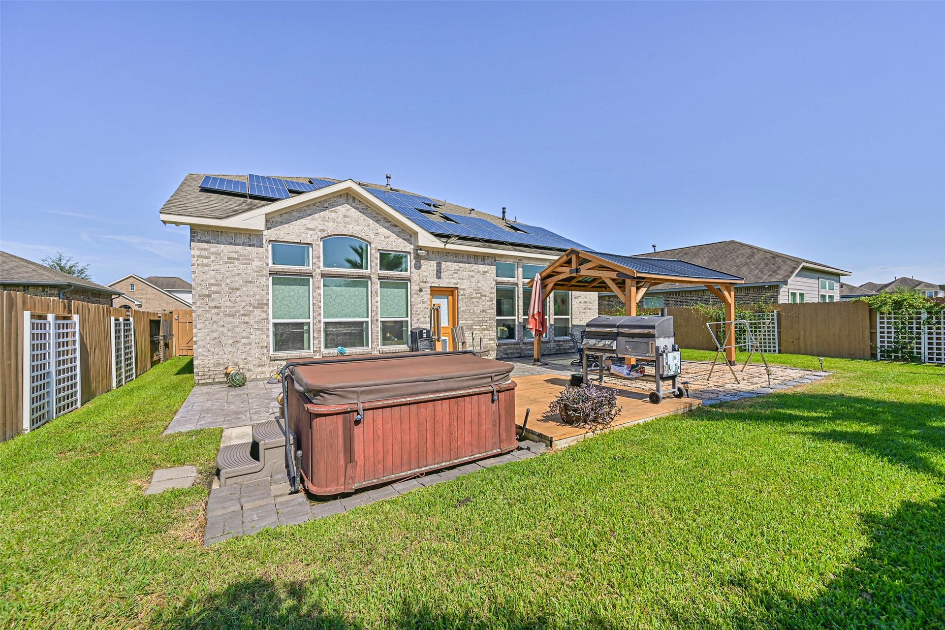 12527 Jetty Cove Drive, Texas City, TX 77568 Beautiful backyard retreat featuring a private hot tub, expansive patio, covered outdoor entertaining area, and solar panels.