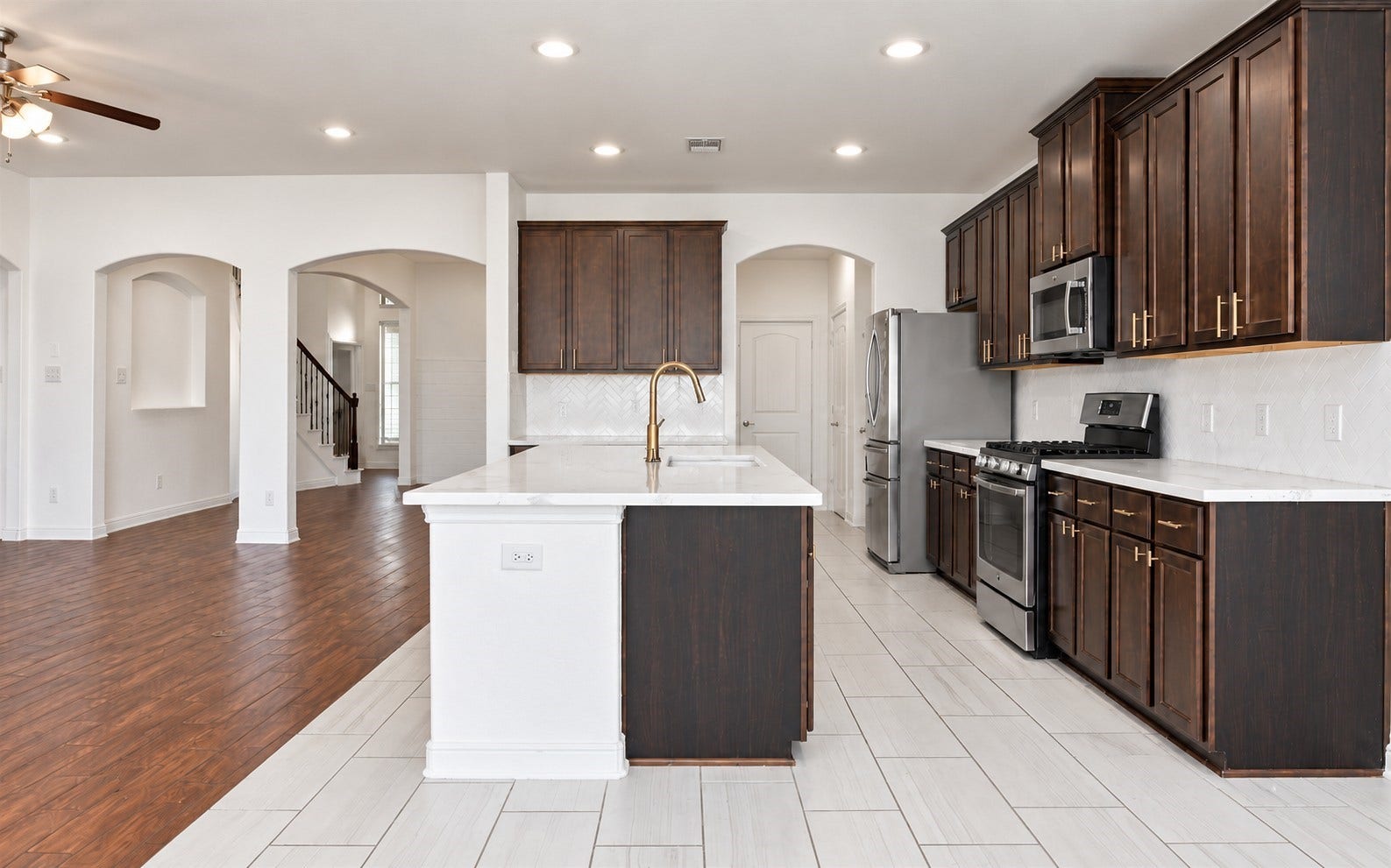 23827 Padauk Tree Trail, Katy, TX 77493 The kitchen is where this home really shines. Dark wood cabinetry, white quartz countertops, gold fixtures, stainless steel appliances and a herringbone tile backsplash making this space look stunning.