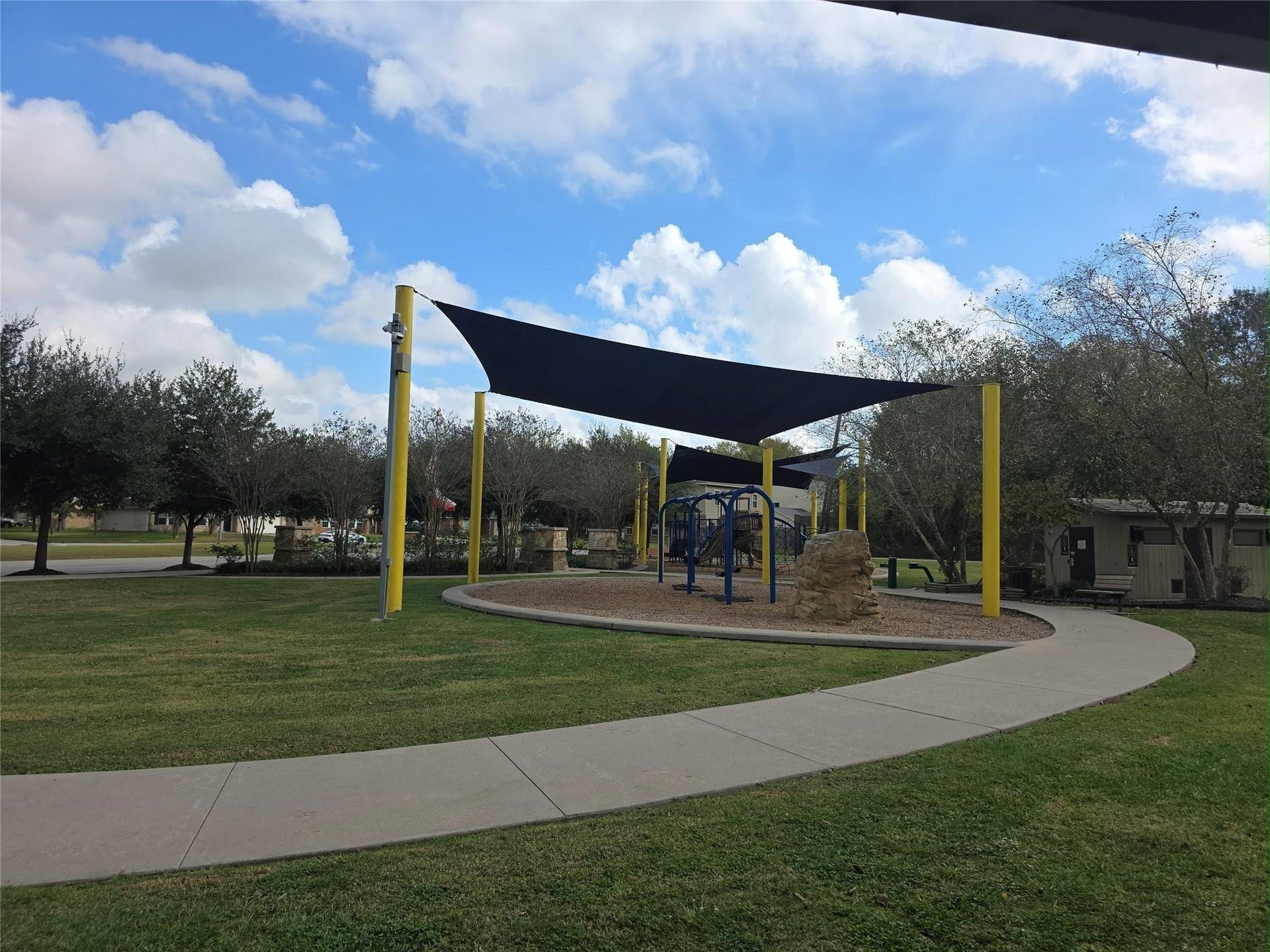 Charming community playground with modern equipment, shaded areas, and a winding path, perfect for family fun and relaxation in a serene neighborhood setting.
