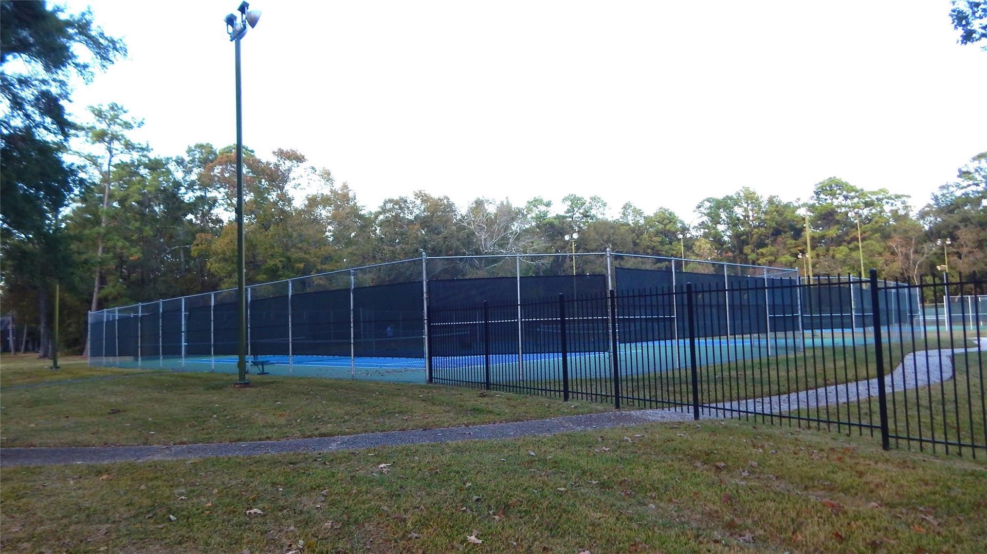 Enjoy a well-maintained tennis court surrounded by lush greenery, perfect for outdoor sports enthusiasts.