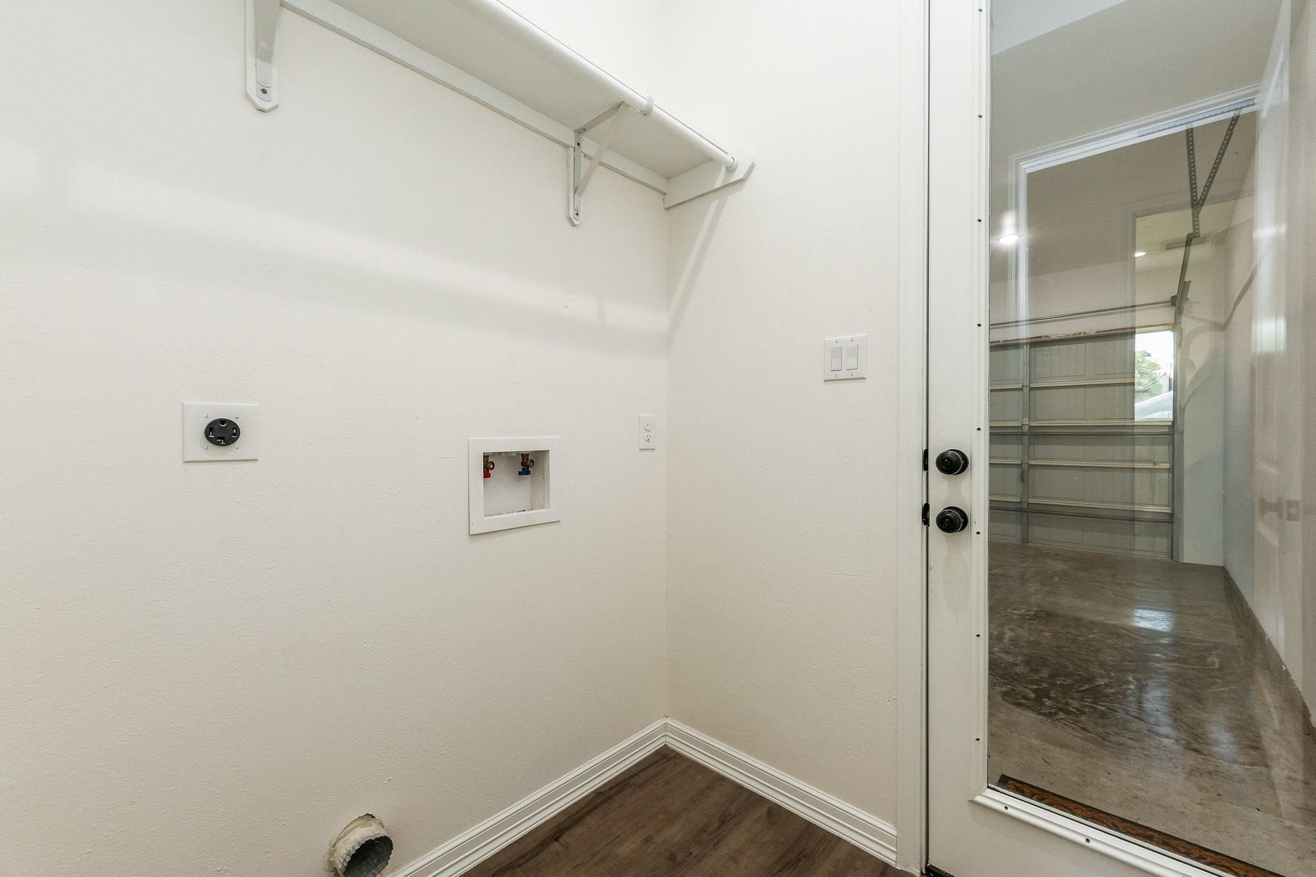 Convenient laundry nook with washer and dryer hookups, featuring easy access to the garage through a sleek glass door.