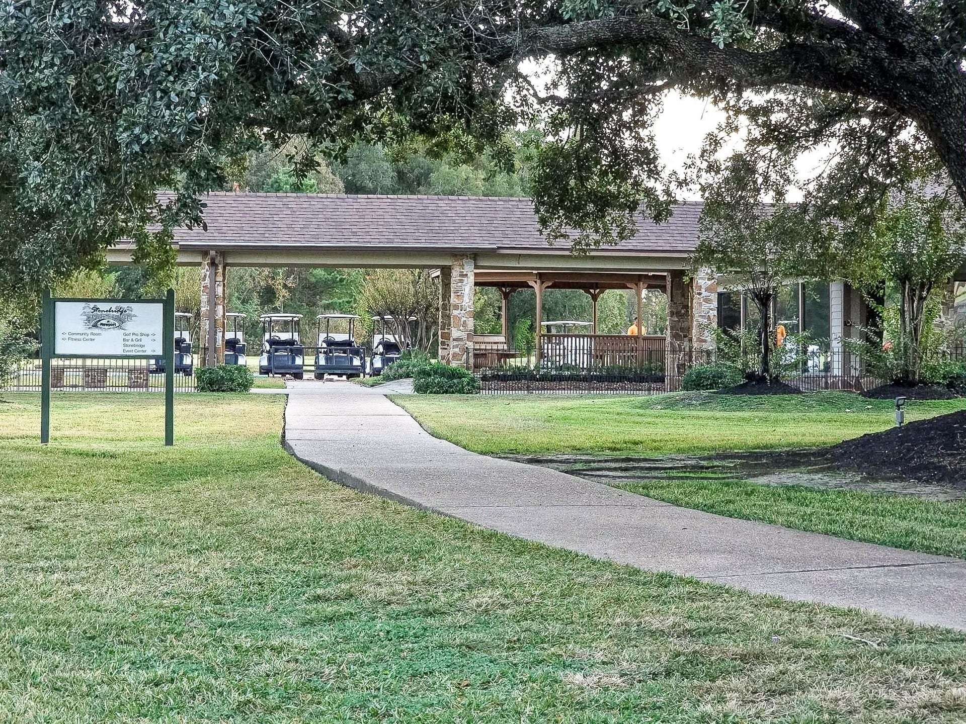 Charming community center with a welcoming porch and golf cart access, surrounded by lush greenery and mature trees.