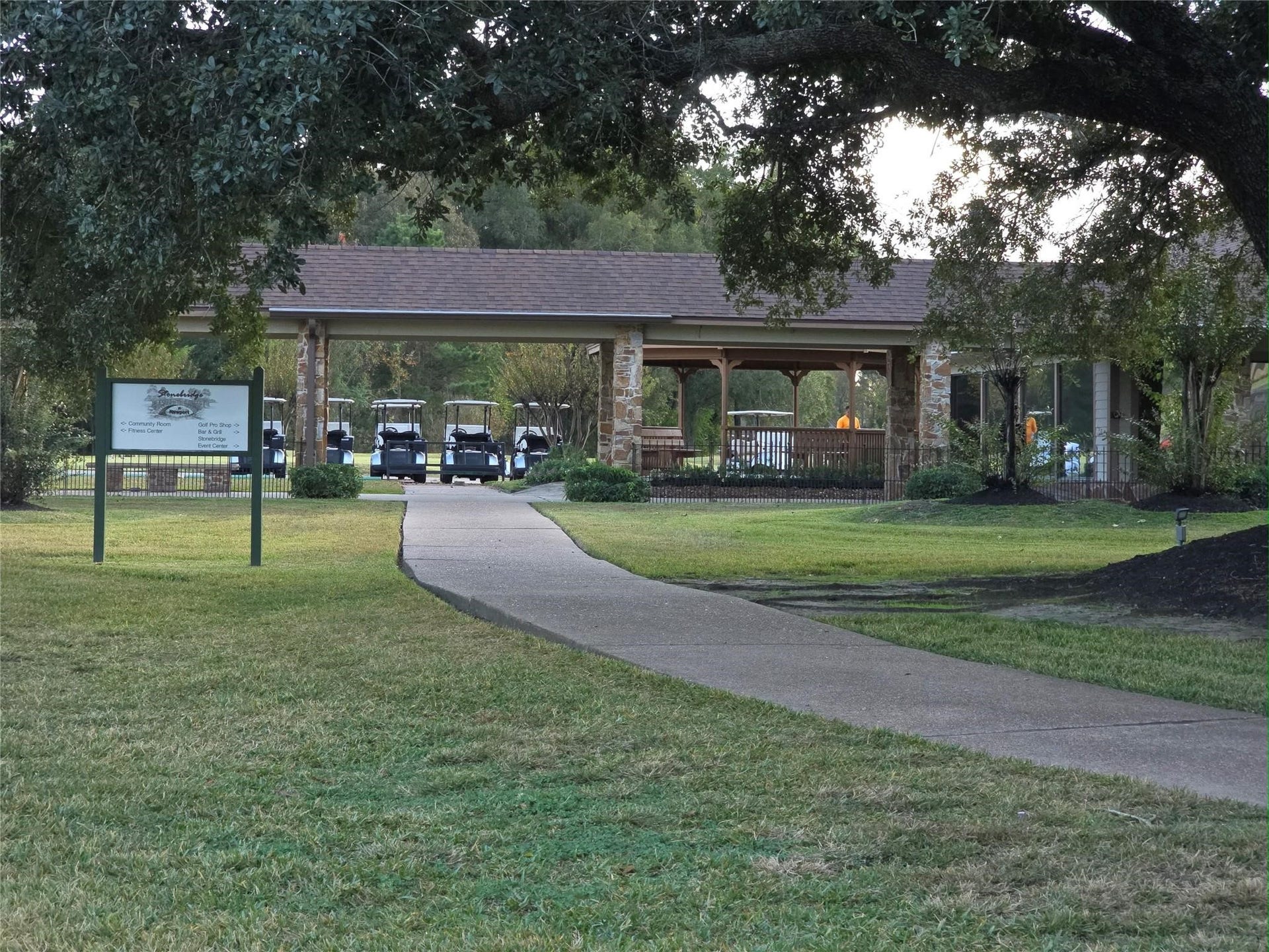Charming clubhouse nestled amidst lush greenery, featuring a welcoming pathway and golf carts ready for a day on the course.